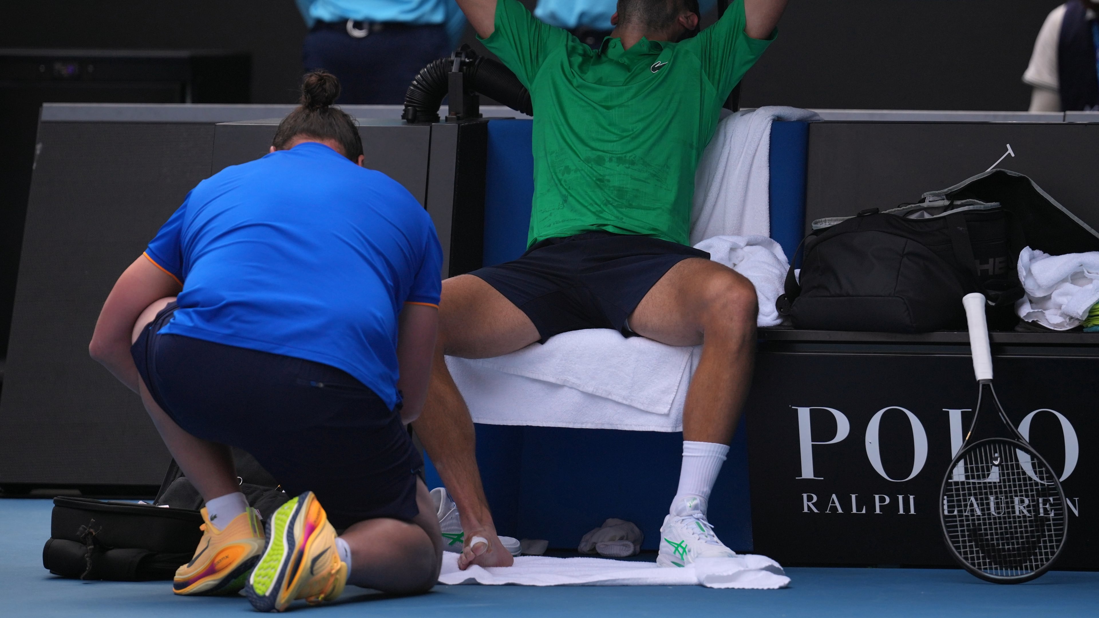 Novak Djokovic of Serbia reacts as he receives treatment to a foot injury during his quarterfinal match against Lorenzo Musetti of Italy at the Australian Open tennis championship in Melbourne, Australia, Wednesday, Jan. 28, 2026. (AP Photo/Dita Alangkara)