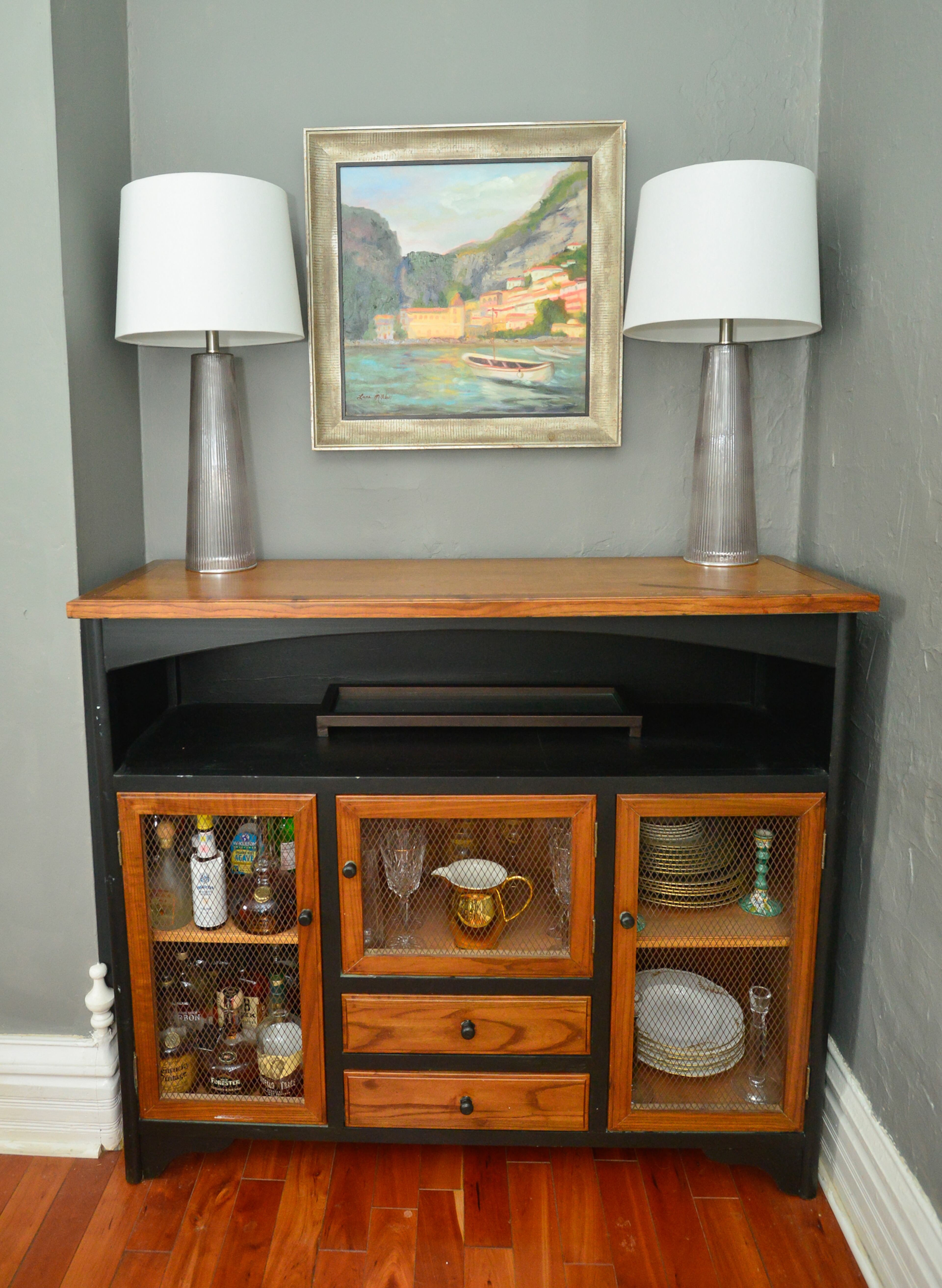 Kendall Stowell bought the bar/buffet cabinet from a showroom at AmericasMart Atlanta, but repainted it from green to black and changed the wood and the fixtures. She likes the wire screens on the cabinet doors. It's below Lana Mitchell's painting of Positano, Italy, where the couple honeymooned.