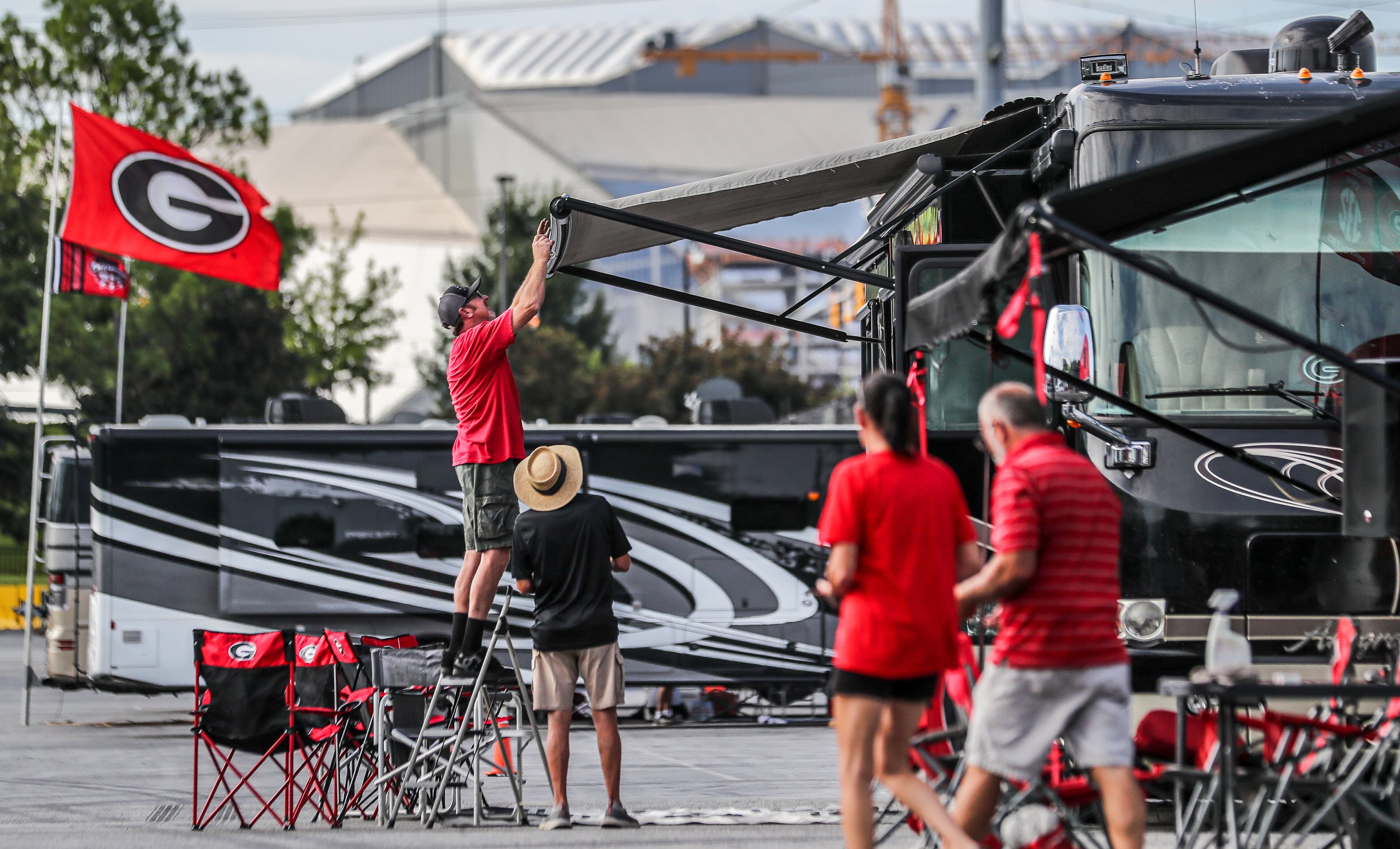 September 2, 2022 Atlanta: Left to right - UGA RV enthusiasts, Brent Lovern from Bogart, Georgia tries to fix the awning of Lindsay Greeson from Winder, Georgia as Melanie and Barton Carty from outside of Monroe, Georgia come around the corner to help at the Marshalling Yard at the Georgia World Congress Center where college football RV enthusiasts are parked. in the shadow of Mercedes-Benz Stadium. College football fans began filtering into downtown Atlanta on Friday, Sept. 2, 2022 for SaturdayÕs big game with the defending College Football National Champions, the Georgia Bulldogs set to take on the #11 Oregon Ducks in the Chick-fil-A kickoff game at Mercedes-Benz Stadium. (John Spink / John.Spink@ajc.com)