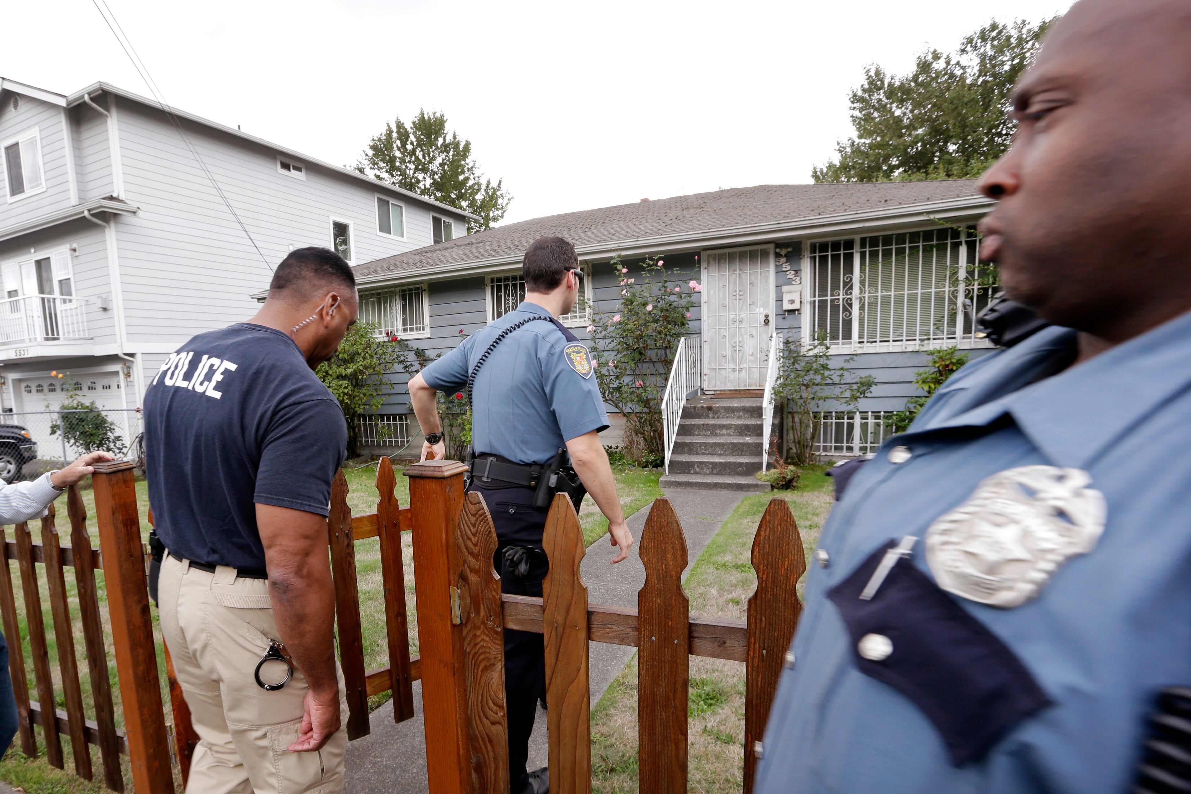 Seattle police officers walk toward a home where Aaron Alexis, the man identified as the shooter in the Washington Navy Yard shootings, has a connection with Monday, Sept. 16, 2013, in Seattle. According to public documents, Alexis lived in Seattle at the home in 2004 and 2005. (AP Photo/Elaine Thompson)