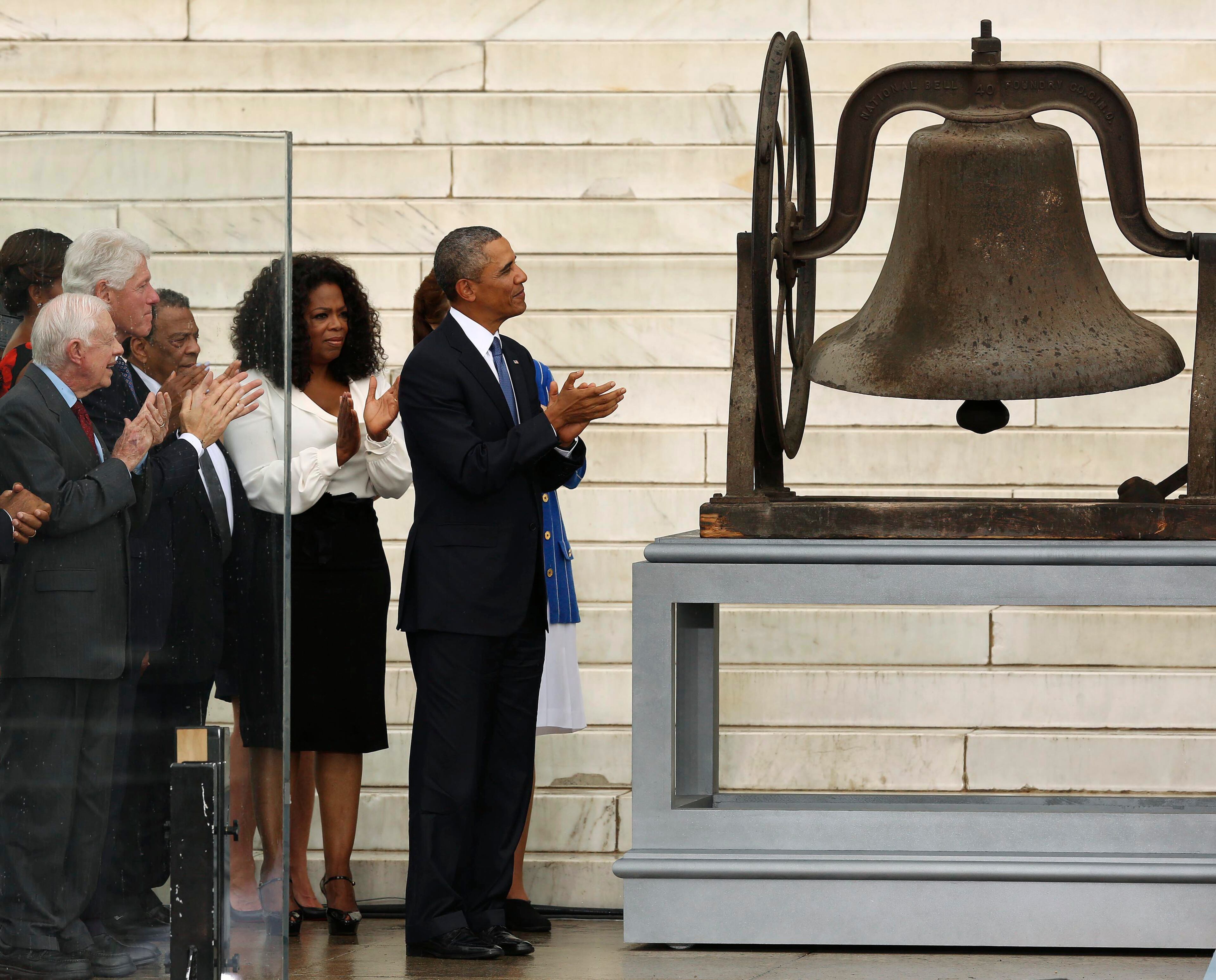 U.S. President Barack Obama (C) applauds the ringing of a Birmingham, Alabama church bell during ceremonies celebrating the 50th anniversary of the 1963 "March on Washington" at the Lincoln Memorial in Washington August 28, 2013. America is struggling to fully realize the vision that civil rights leader Martin Luther King described in his famous "I have a dream" speech 50 years ago, as the goal of economic security for all remains elusive, Obama said on Wednesday. Also pictured are former U.S. presidents, Jimmy Carter (L) and Bill Clinton (2nd L), and Oprah Winfrey (3rd L). REUTERS/Gary Cameron (UNITED STATES - Tags: ANNIVERSARY POLITICS ENTERTAINMENT)