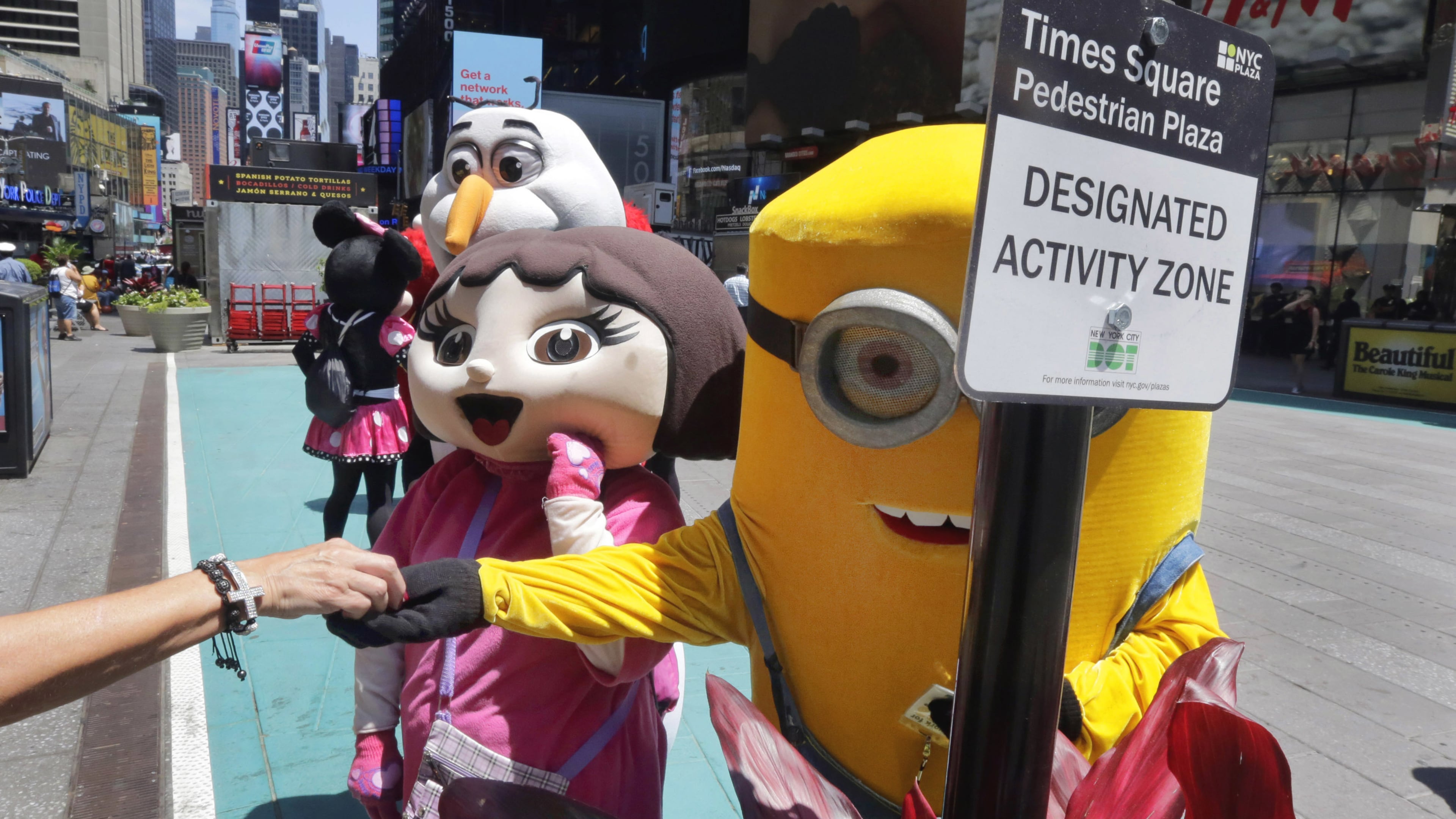 Costumed characters work in a color-coded designated activity zone in New York’s Times Square, Tuesday, June 21, 2016. Street performers and costumed characters can be issued summonses or face arrest if they’re caught operating outside the eight designated rectangles, under new rules aimed at controlling overly aggressive street performers. Each area is painted teal and measures 8 feet by 50 feet. (AP Photo/Richard Drew)