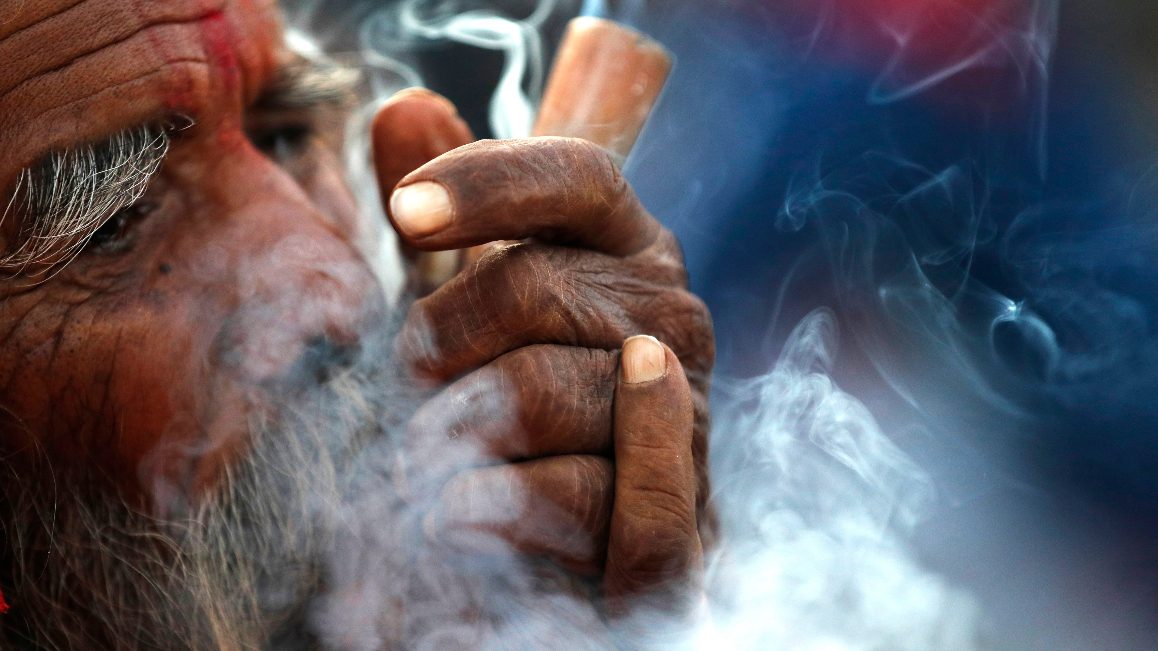 FILE- In this March 11, 2021, file photo, a Hindu holy man smokes marijuana in the courtyard of Pashupatinath temple during Shivratri festival in Kathmandu, Nepal. (AP Photo/Niranjan Shrestha, File)