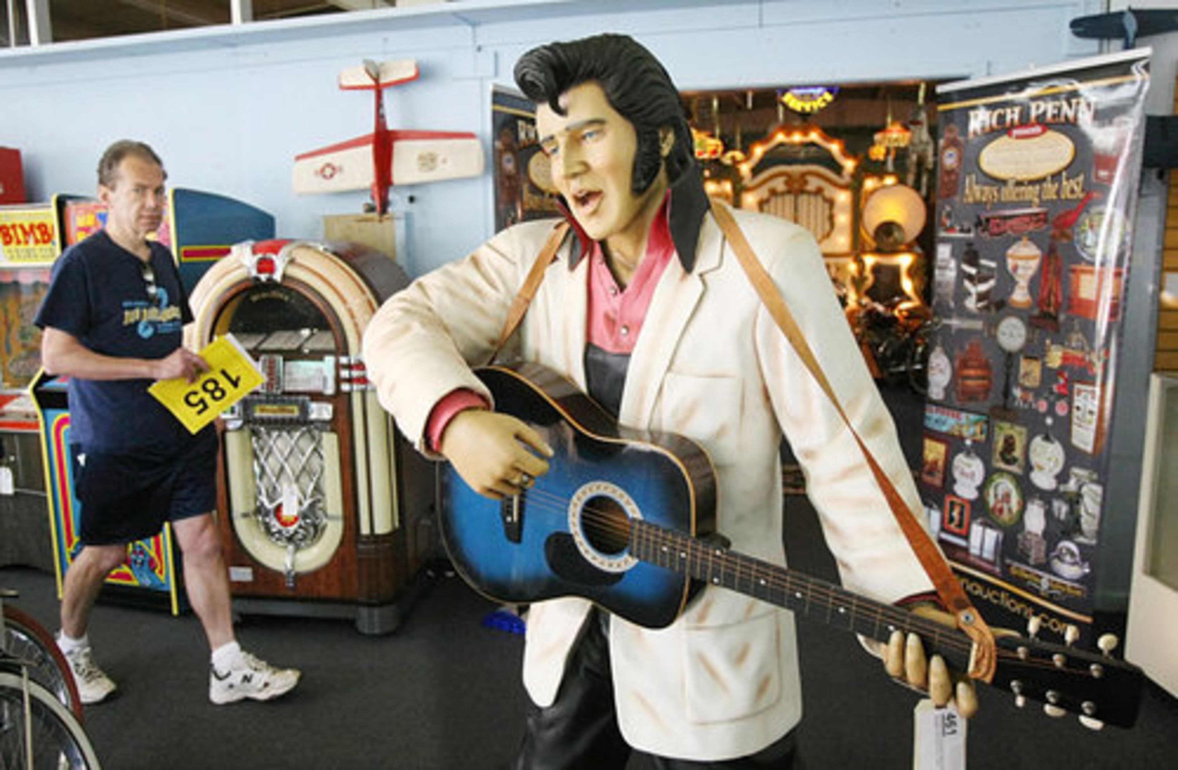 A bidder walks past a life-sized figure of Elvis Presley.