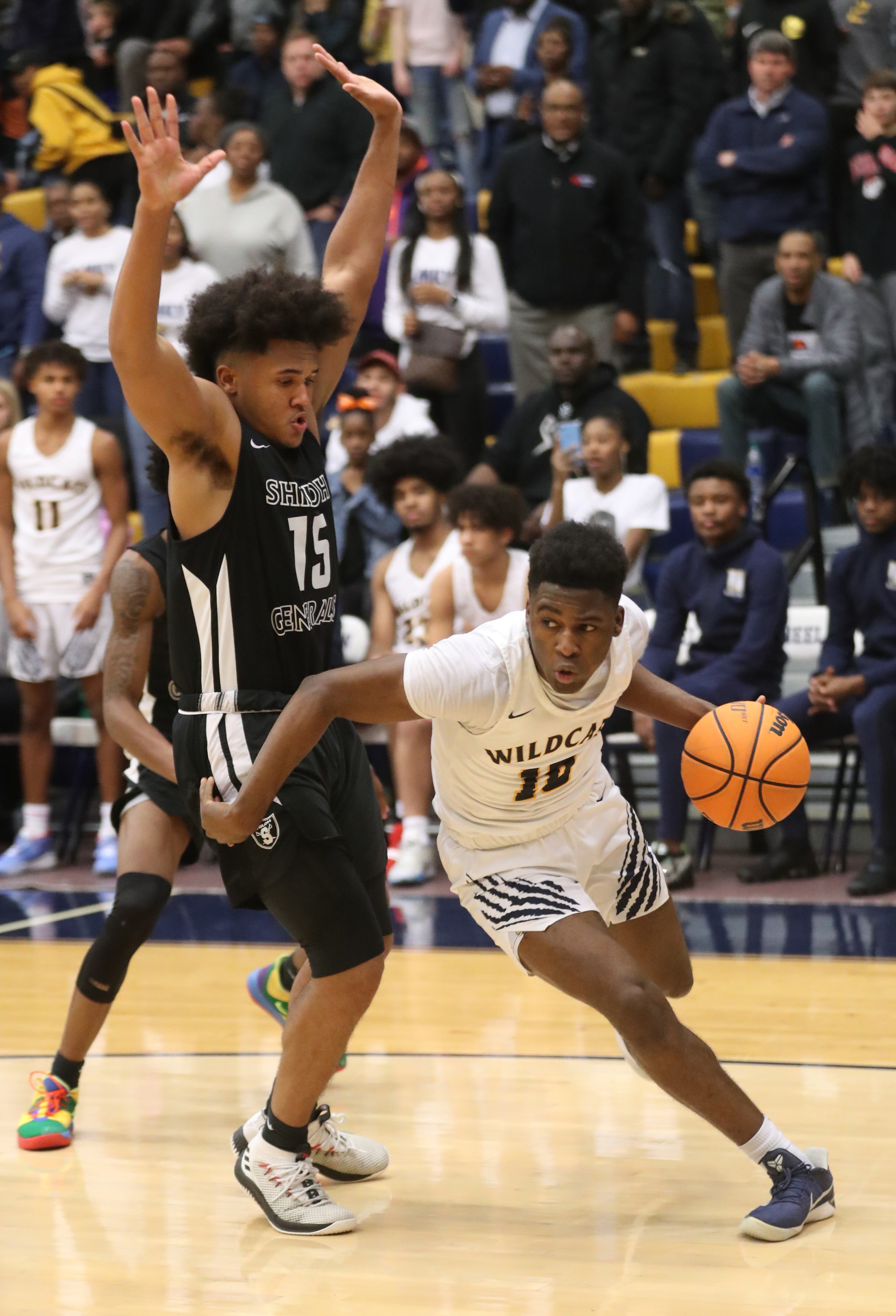 Wheeler guard Nash Kelly (10) drives against Shiloh guard Antonio Meeks (15) in overtime as the Wildcats defeated Shiloh 65-64 Thursday in the second round of the Class AAAAAAA state tournament. (Jason Getz/Special to the AJC)