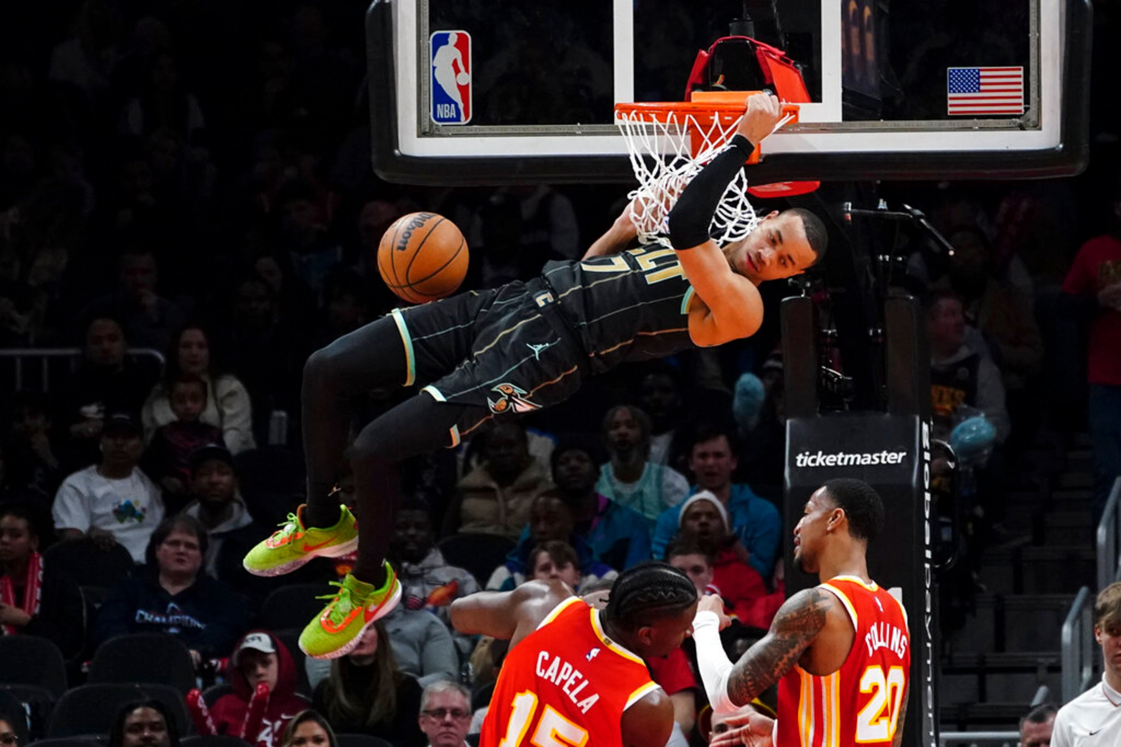 Charlotte Hornets guard Bryce McGowens (7) scores as Atlanta Hawks center Clint Capela (15) and forward John Collins (20) look on during the first half of an NBA basketball game Saturday, Jan. 21, 2023, in Atlanta. The Hawks lost 122-118. (AP Photo/John Bazemore)