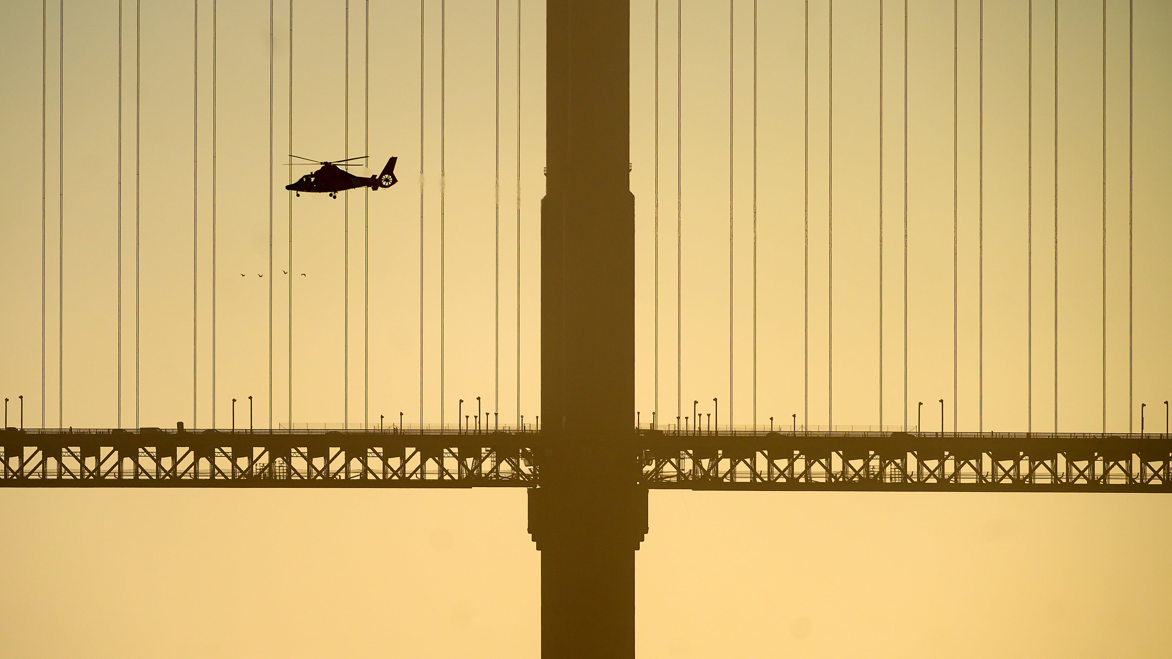 A helicopter flies past the Golden Gate Bridge while searching for missing victims after a boat accident near Alcatraz Island off San Francisco, Tuesday, July 14, 2026. (AP Photo/Noah Berger)
