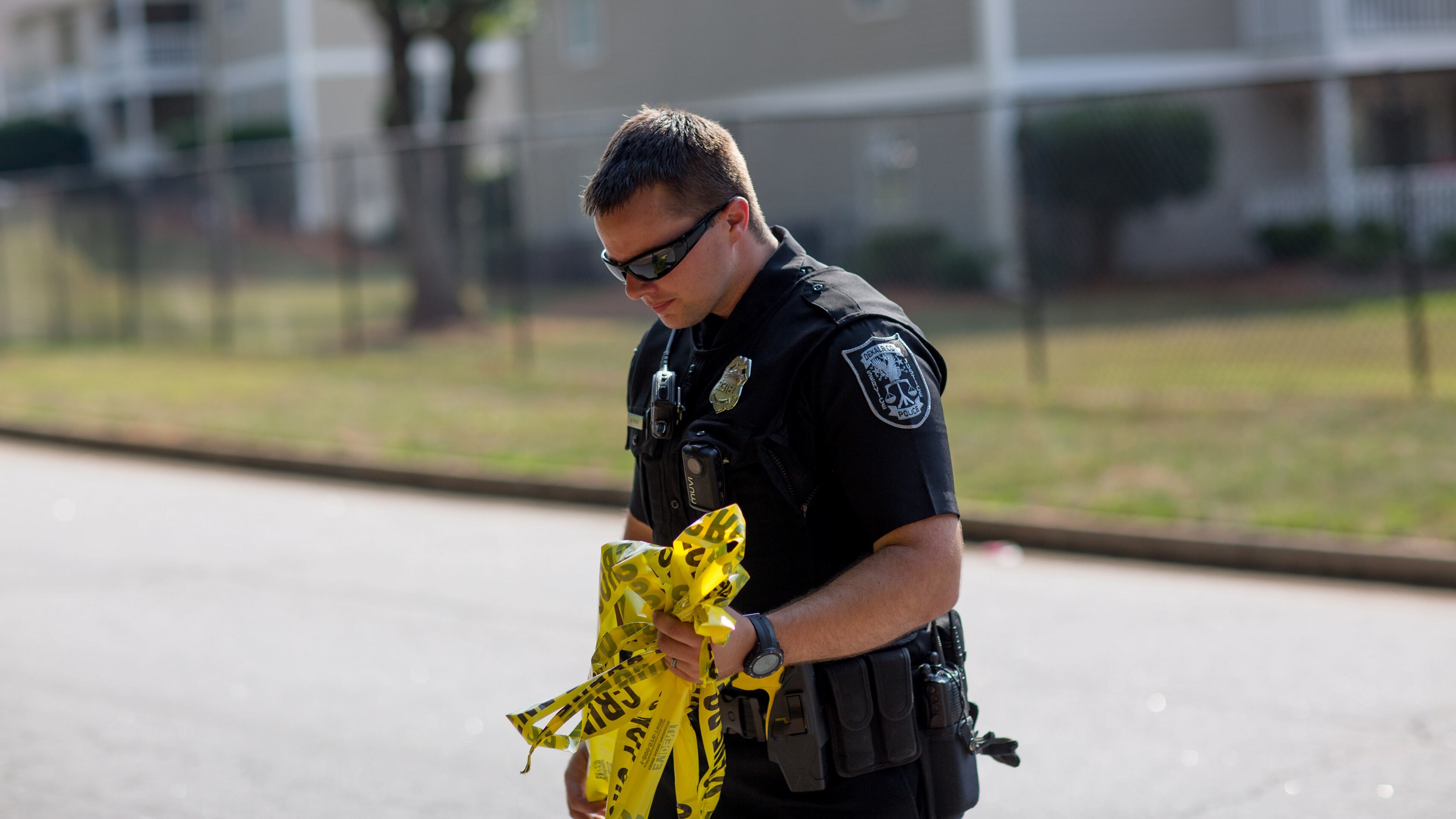 A DeKalb County police officer carries crime scene tape near where four people were critically wounded and one was killed during a drug deal on Lancashire Drive near Stone Mountain, Wednesday, June 22, 2016, in DeKalb County. BRANDEN CAMP/SPECIAL