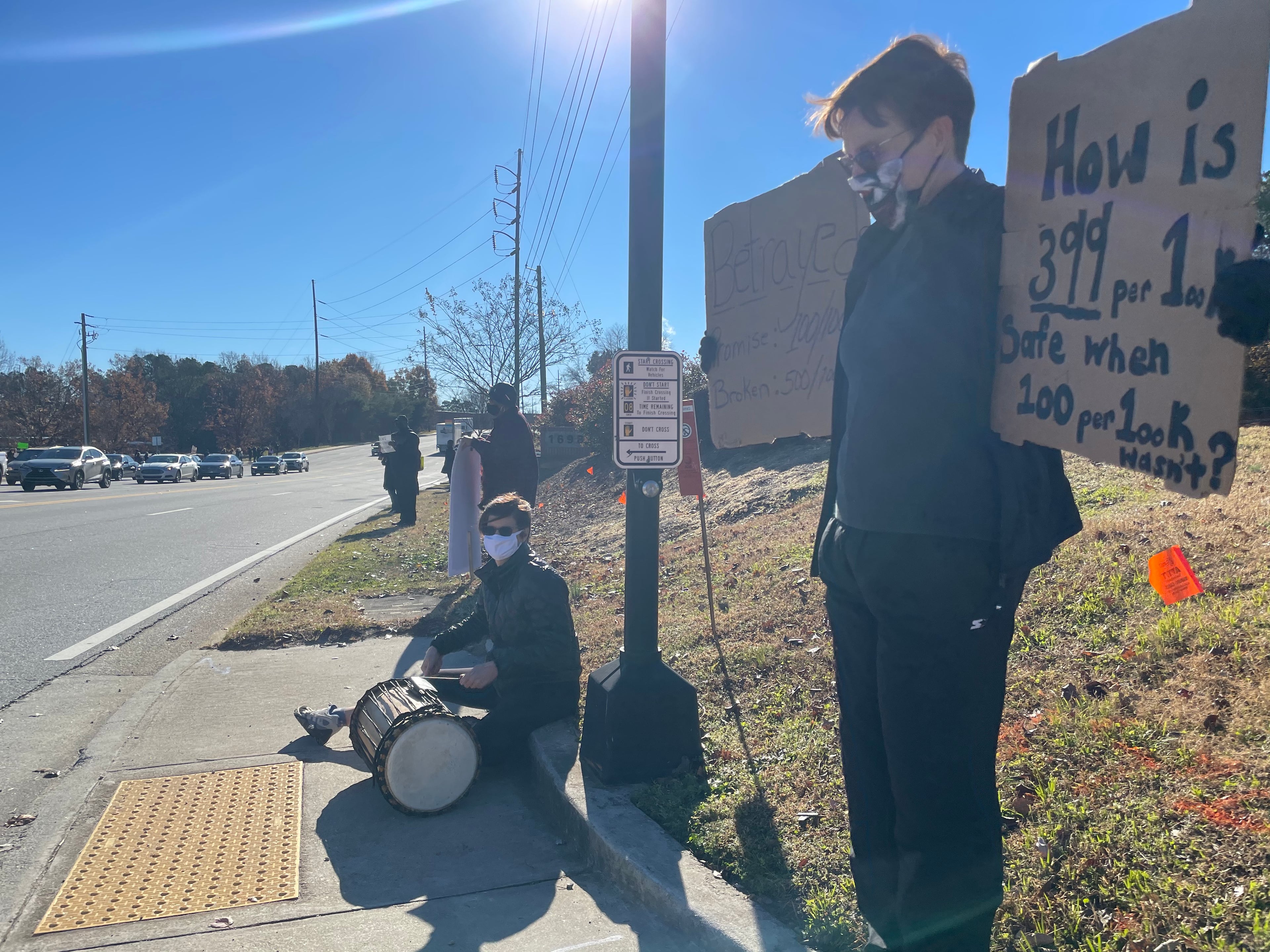Community members in DeKalb held signs on Tuesday to protest against the reopening of DeKalb County schools.