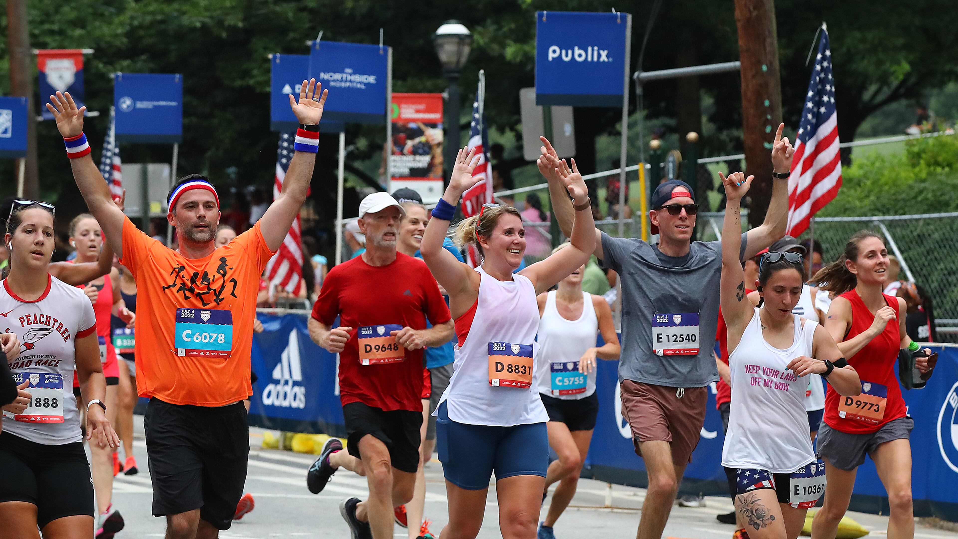 070422 Atlanta: Runners begin to celebrate as they approach the finish line in the AJC Peachtree Road Race on Monday, July 4, 2022, in Atlanta. “Curtis Compton / Curtis.Compton@ajc.com”