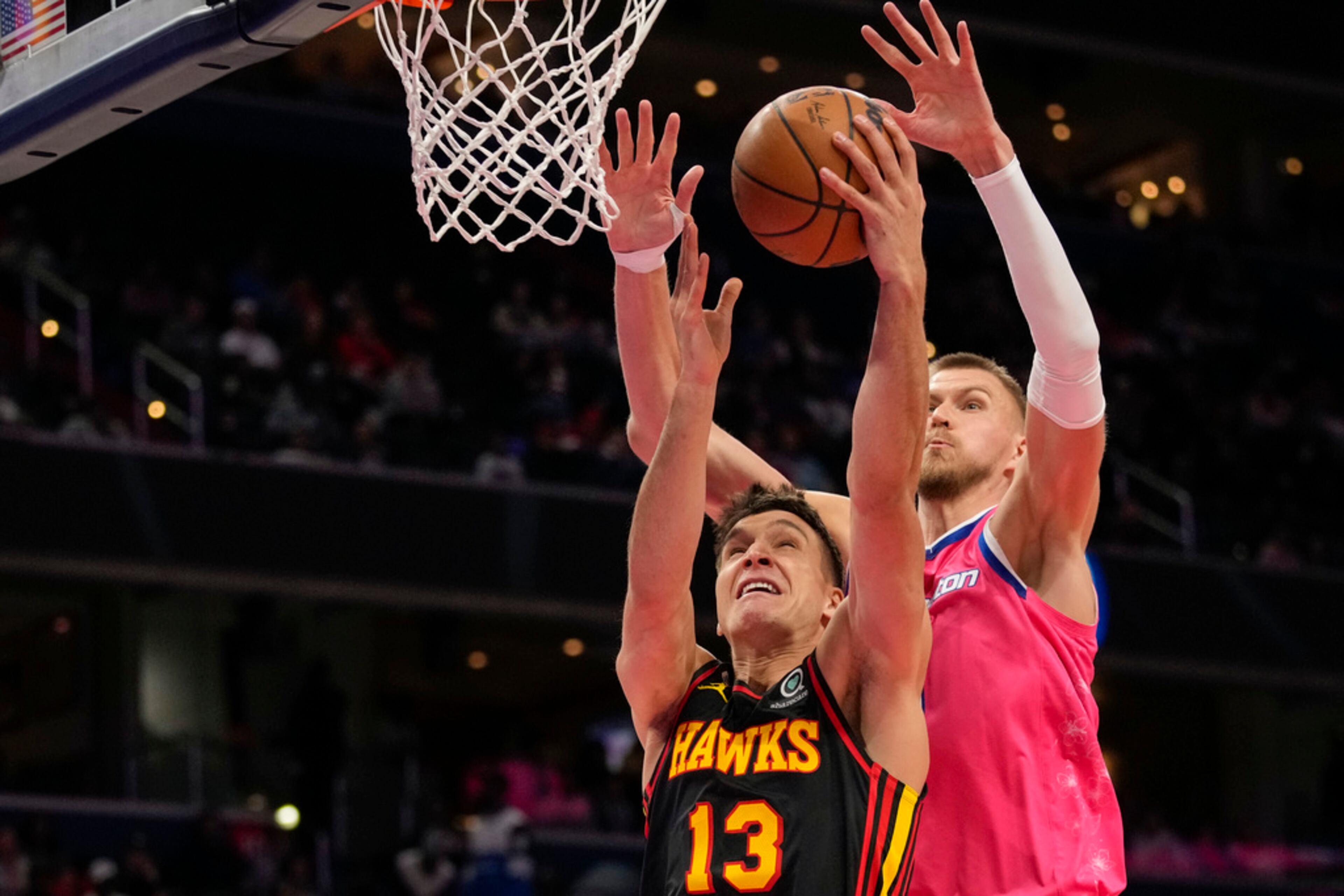 Atlanta Hawks guard Bogdan Bogdanovic (13) shoots in front of Washington Wizards center Kristaps Porzingis (6) during the second half of an NBA basketball game Wednesday, March 8, 2023, in Washington. The Hawks won 122-120. (AP Photo/Alex Brandon)