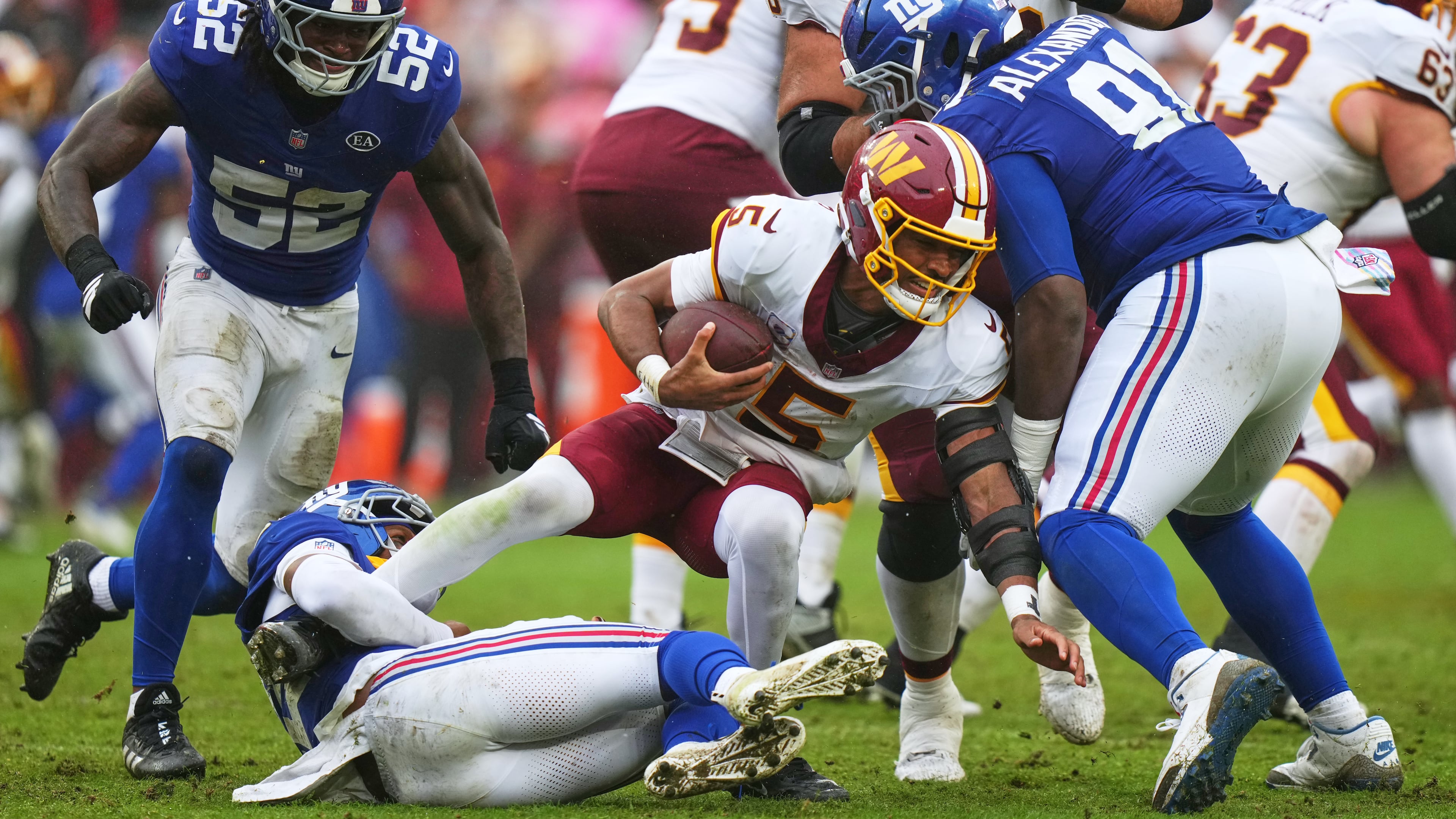 New York Giants' Dru Phillips (22) tackles Washington Commanders quarterback Jayden Daniels (5) as he runs past Darius Alexander (91) and Arvell Reese (52) during the second half of an NFL football game in Landover, Md., Sunday, Oct. 11, 2026. (AP Photo/Stephanie Scarbrough)