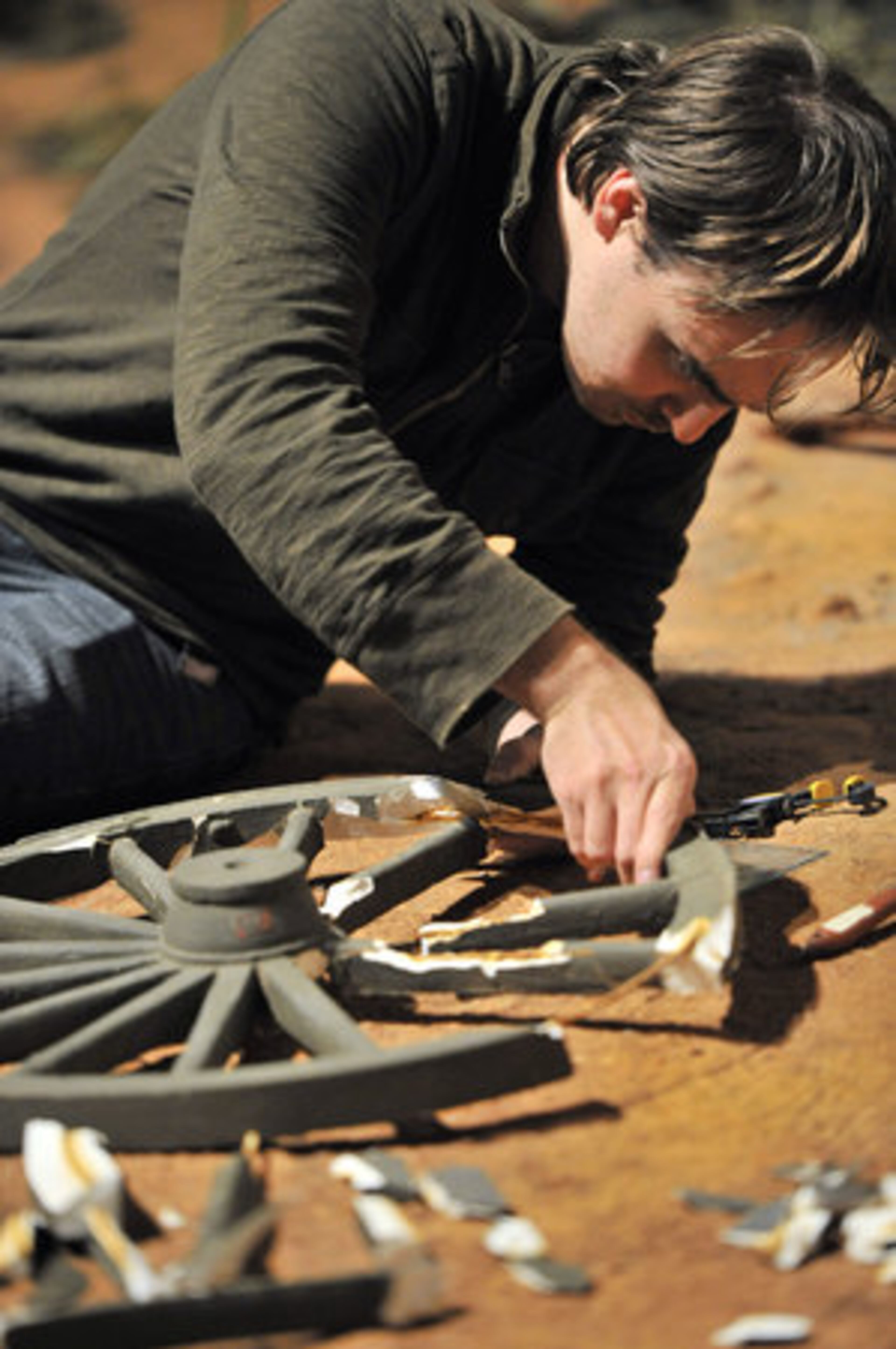 Jason Cochrane, who is working as a volunteer with The Avery Gallery of Marietta, repairs a wagon wheel during the annual cleanup.