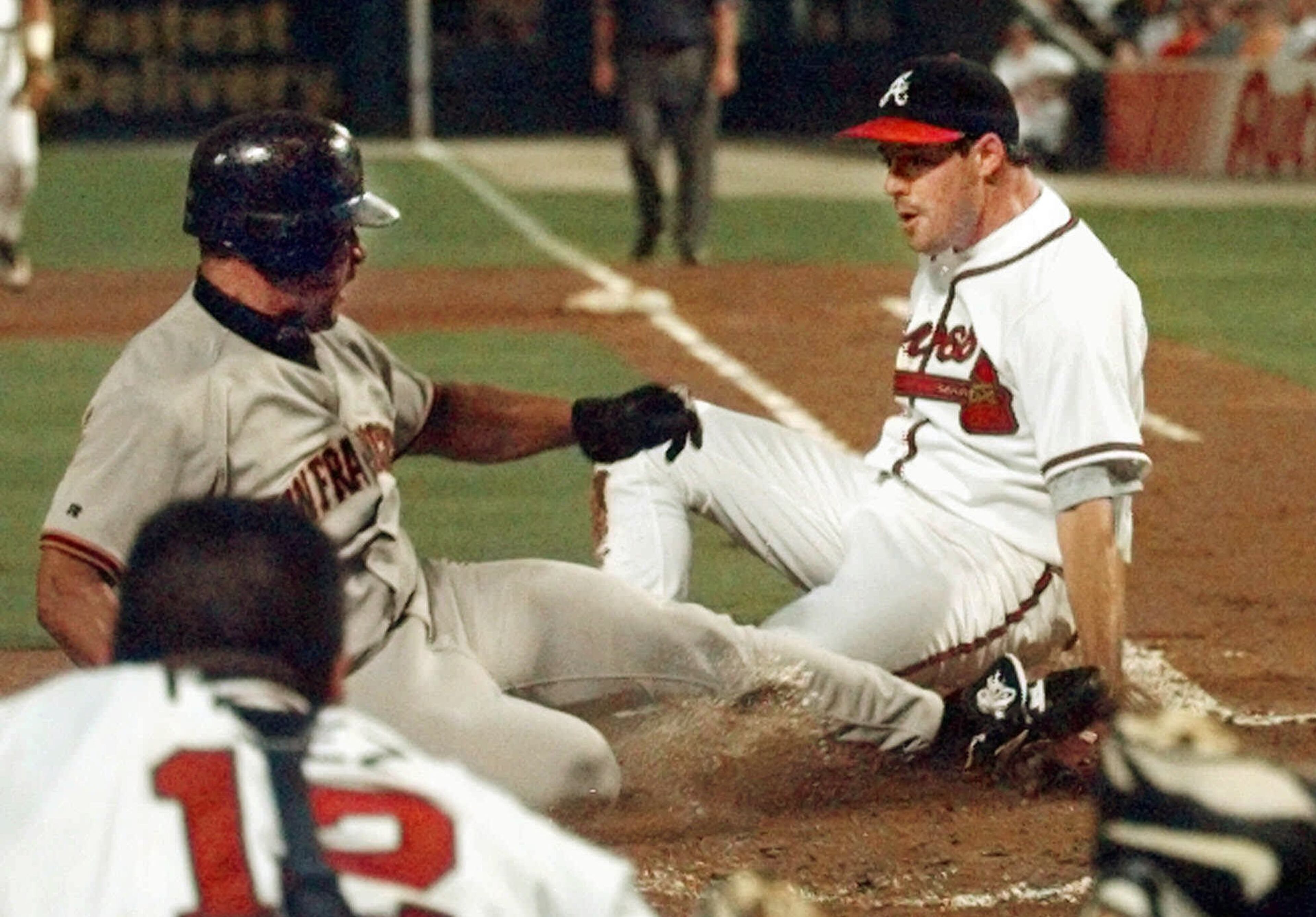 San Francisco Giants base runner Marvin Benard scores on a wild pitch as he slides passed the tag of Atlanta Braves pitcher Greg Maddux.