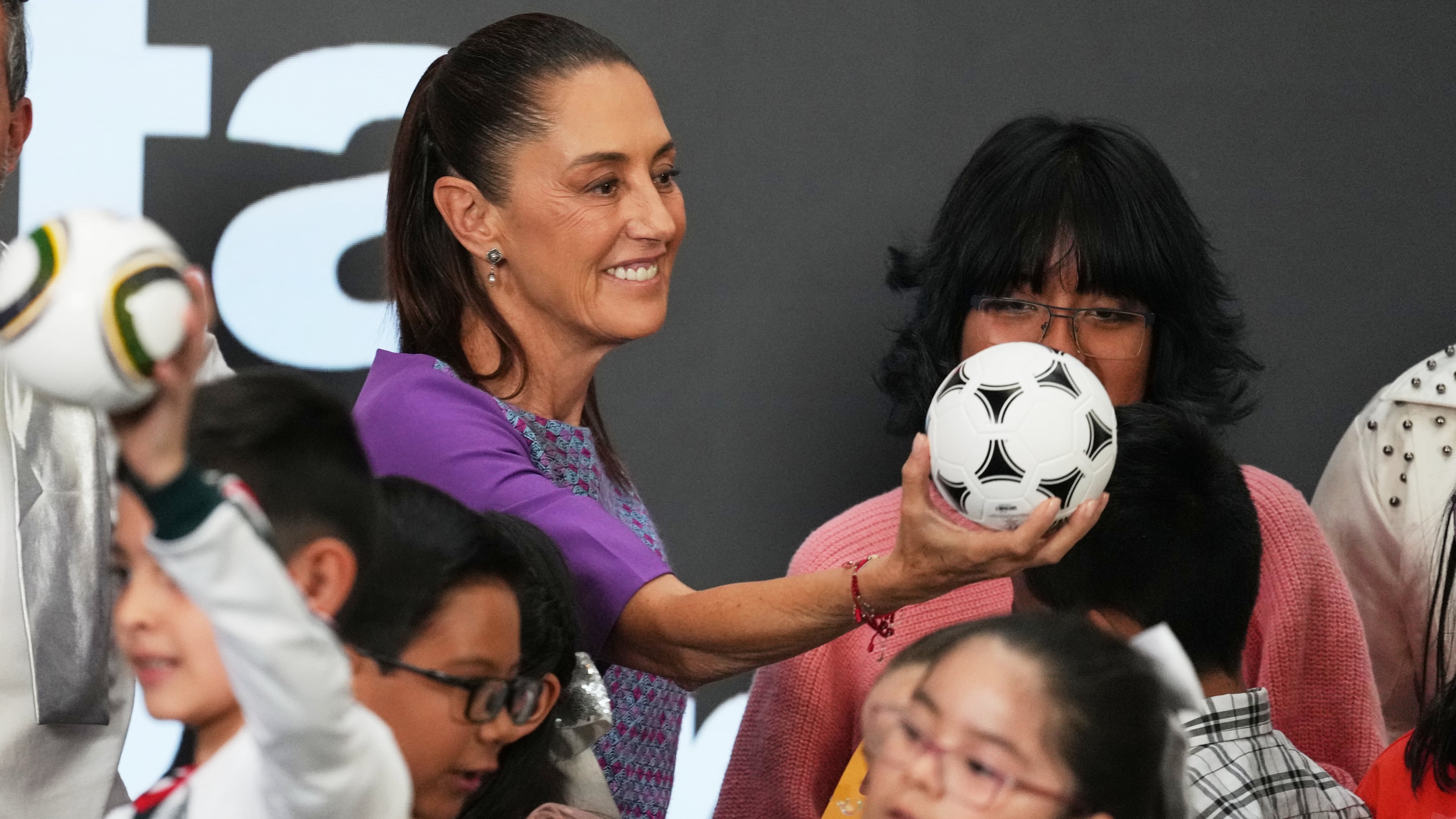 Mexican President Claudia Sheinbaum gives a soccer ball to children after her daily morning press conference at the National Palace in Mexico City, Thursday, April 30, 2026. (AP Photo/Fernando Llano)