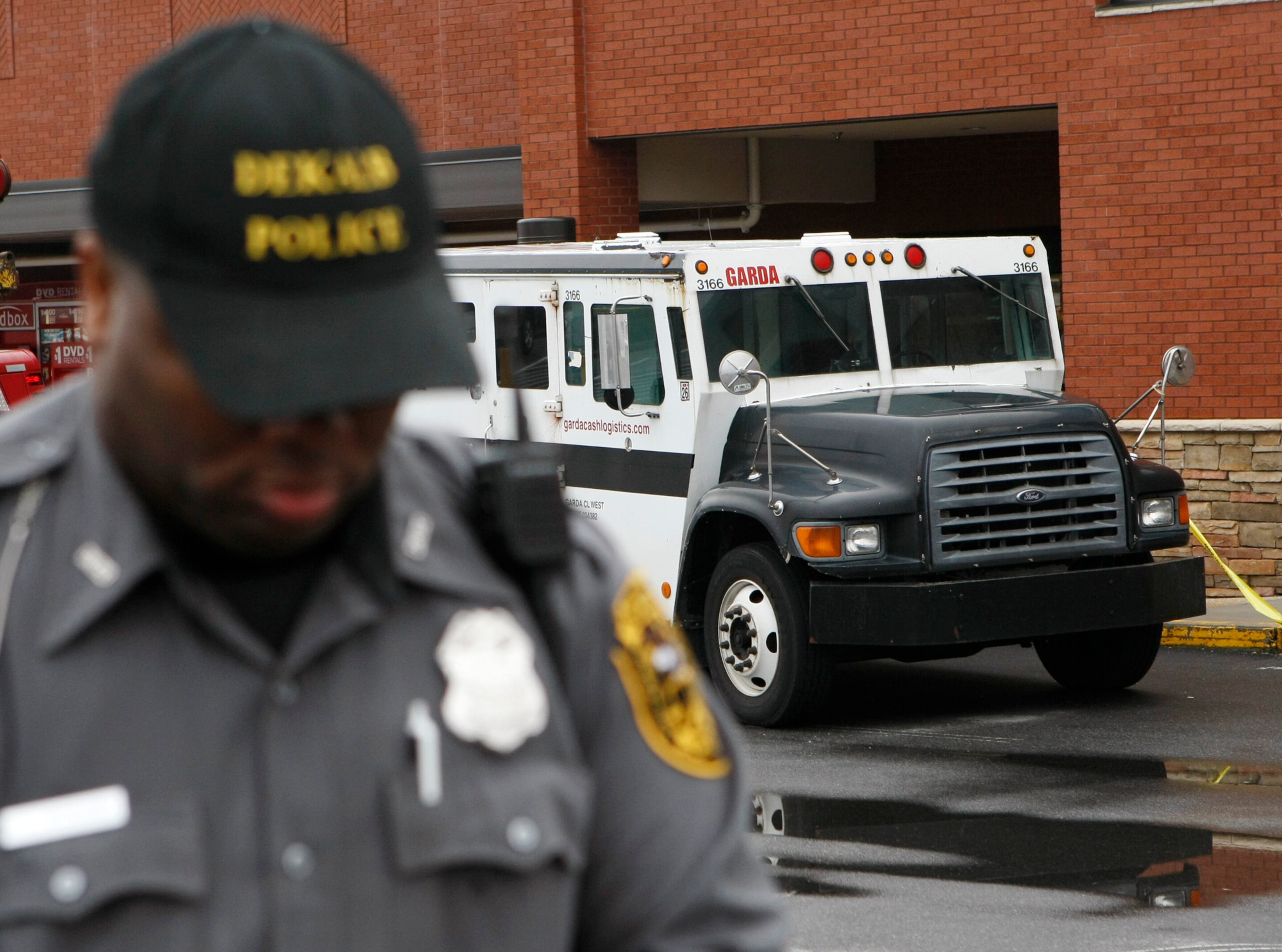 A DeKalb County police officer helps secure the scene following a fatal armored car robbery after 2 men killed a guard in a daring robbery at the Kroger on Lavista Road at North Druid Hills in Atlanta on Tuesday, March 15, 2011.