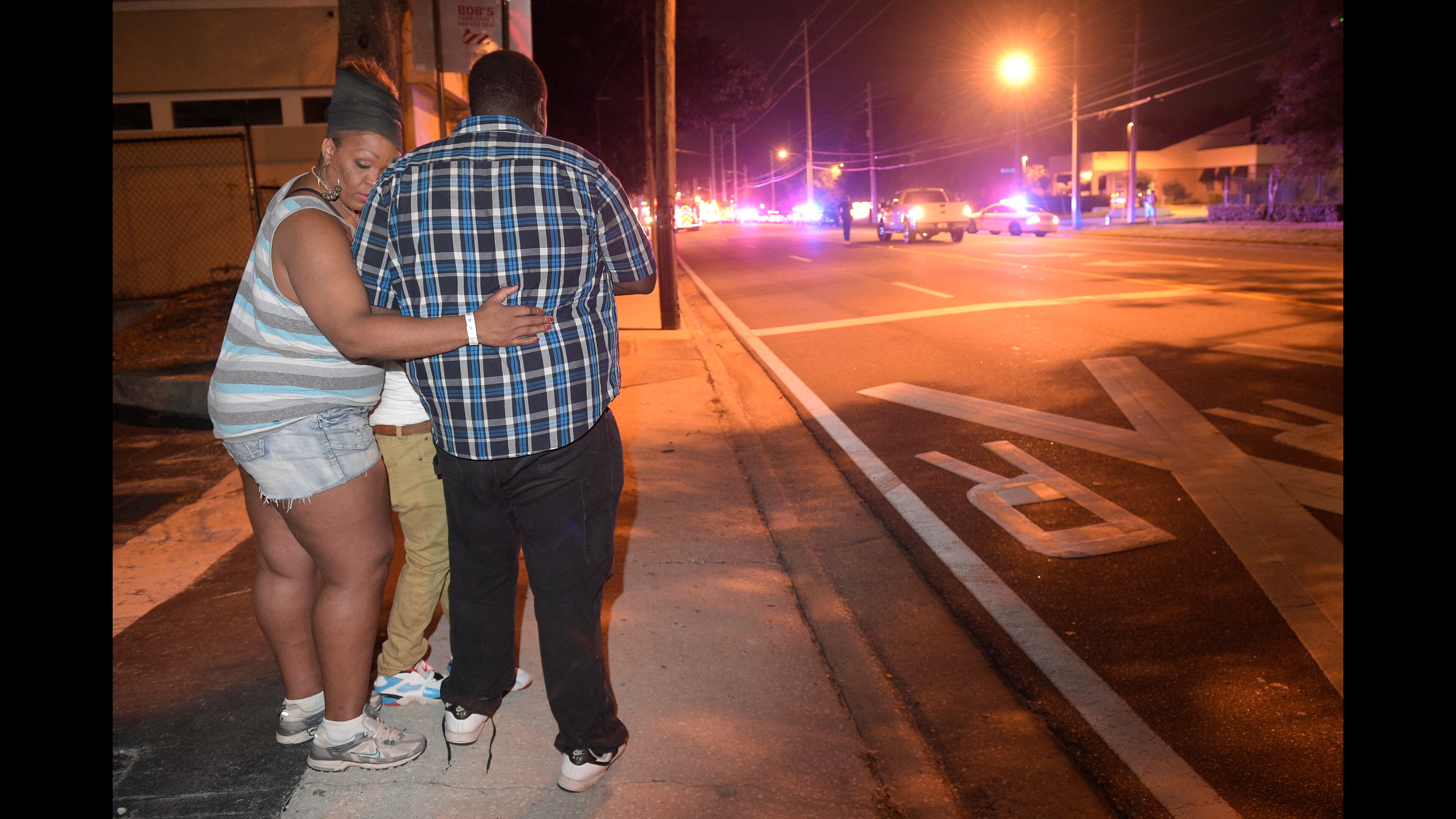 Bystanders wait down the street from a multiple shooting at the Pulse nightclub in Orlando, Fla., Sunday, June 12, 2016. A gunman opened fire at a nightclub in central Florida, and multiple people have been wounded, police said Sunday. (AP Photo/Phelan M. Ebenhack)