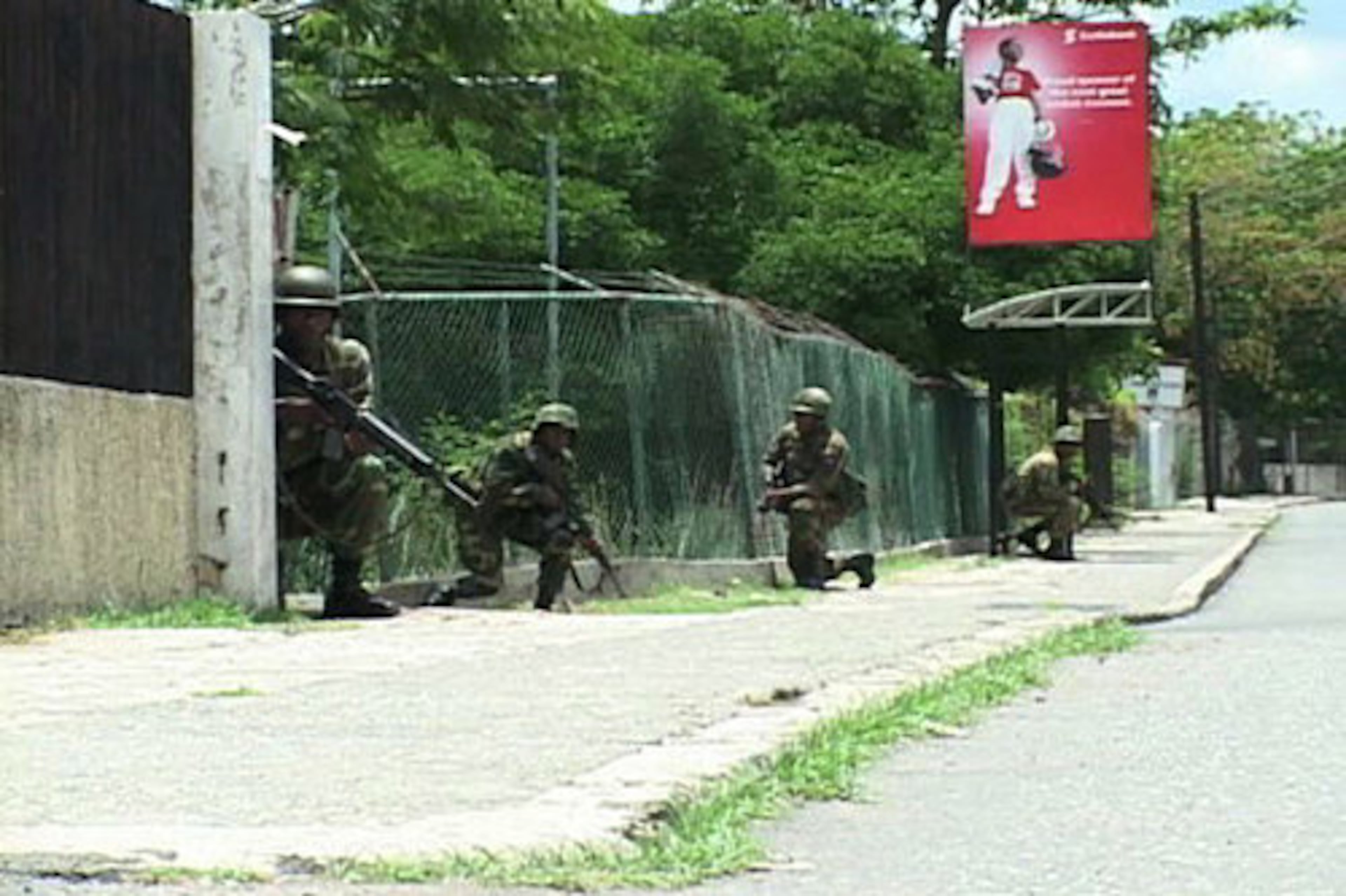 Jamaican army troops taking cover during operations in Kingston, Jamaica, this week. Thousands of police and soldiers stormed the Jamaican ghettos in search of a reputed drug kingpin wanted by the United States, intensifying street battles that have killed at least 40 people.