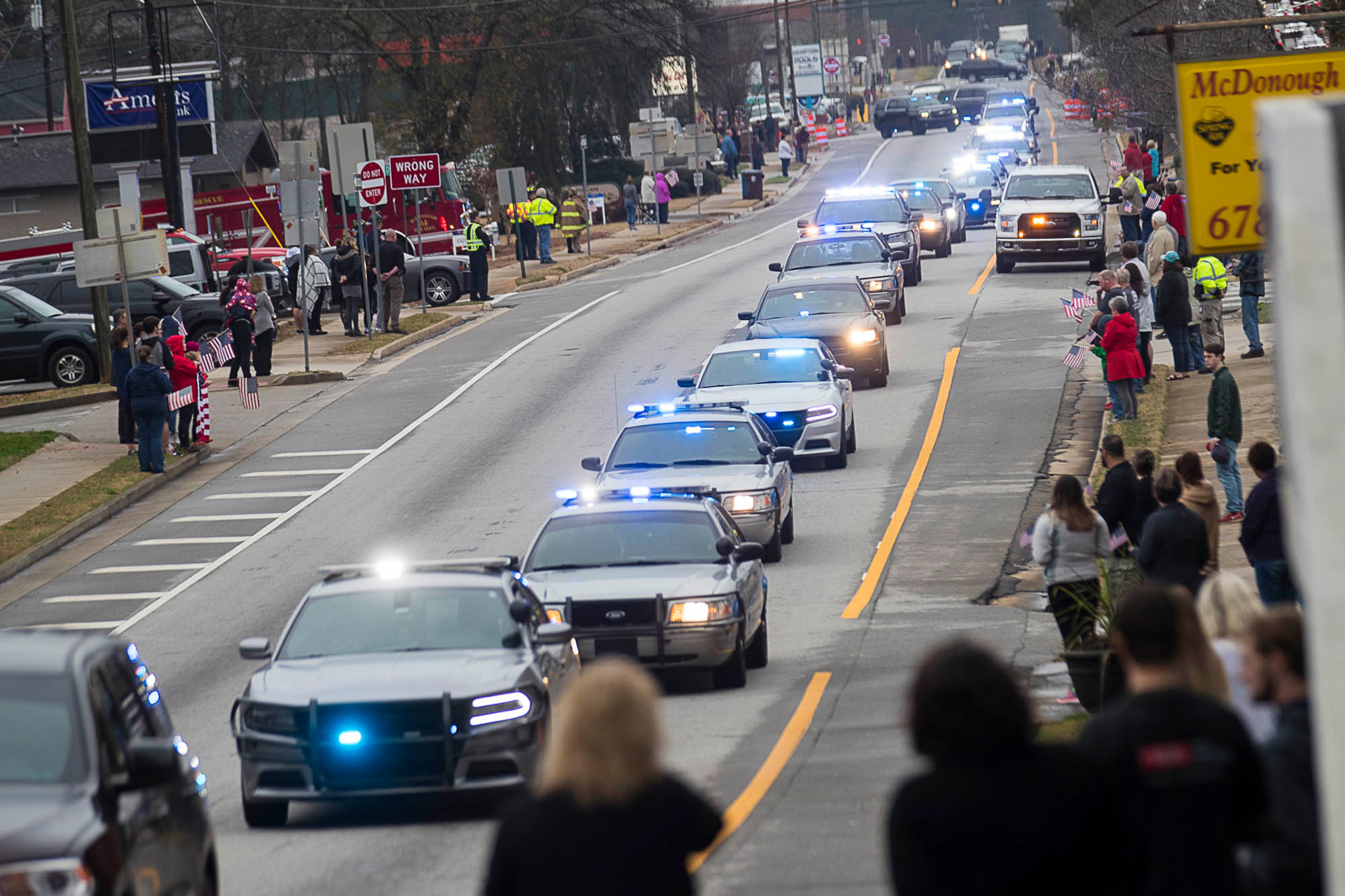 01/03/2019 -- McDonough, Georgia -- Supporters line the John Frank Ward Boulevard as the funeral procession for slain Henry County Police Officer Michael Smith travels through McDonough Squared in McDonough, Thursday, January 3, 2019. Henry County police Officer Michael Smith died from injuries from a gunshot wound he received while responding to a report of a irate man at a McDonough-area dental office. (ALYSSA POINTER/ALYSSA.POINTER@AJC.COM)
