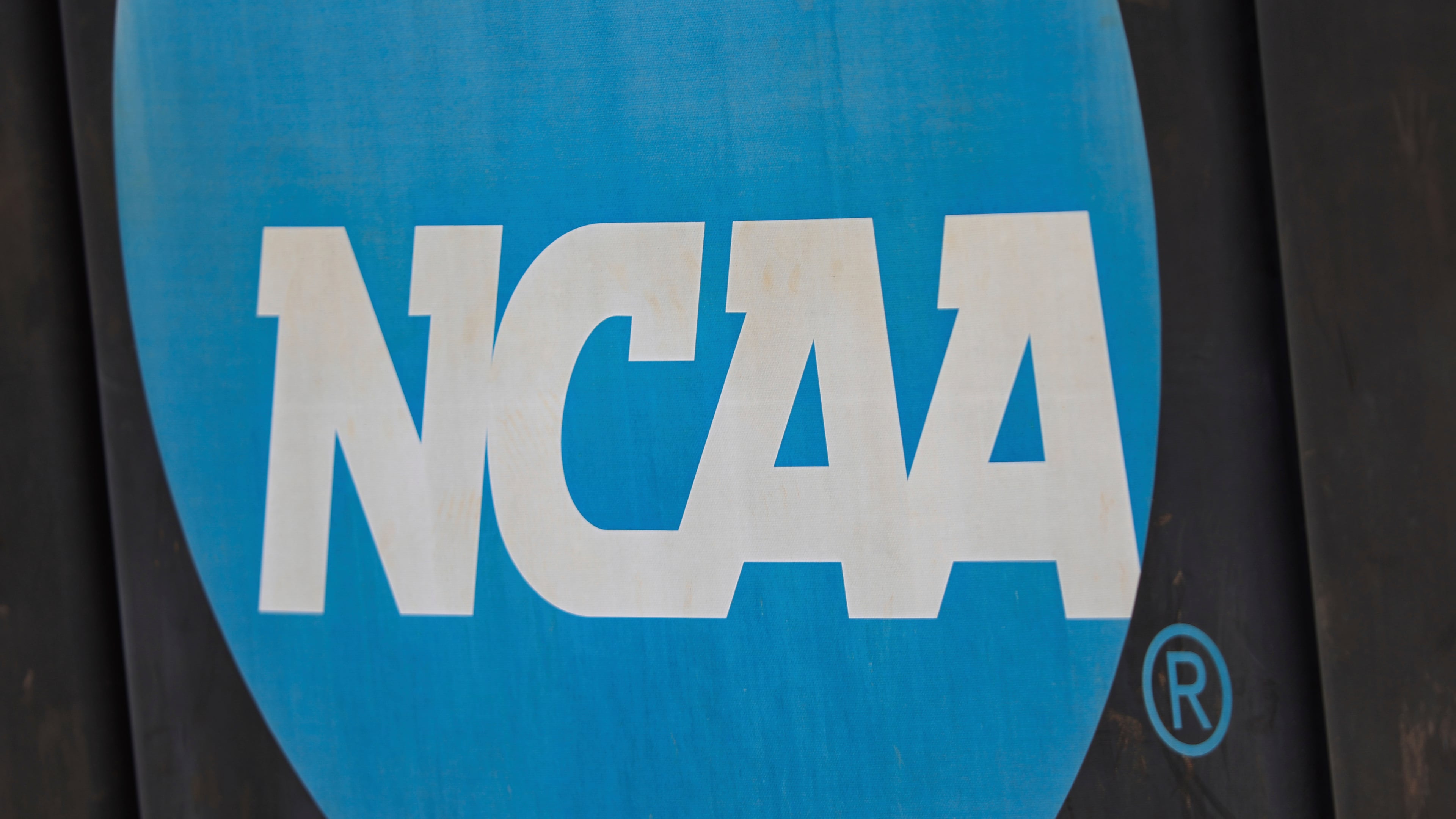 FILE - NCAA logo displayed on the fence before an NCAA softball game between Jacksonville and FGCU, March 24, 2024, in Jacksonville, Fla. (AP Photo/Gary McCullough, File)