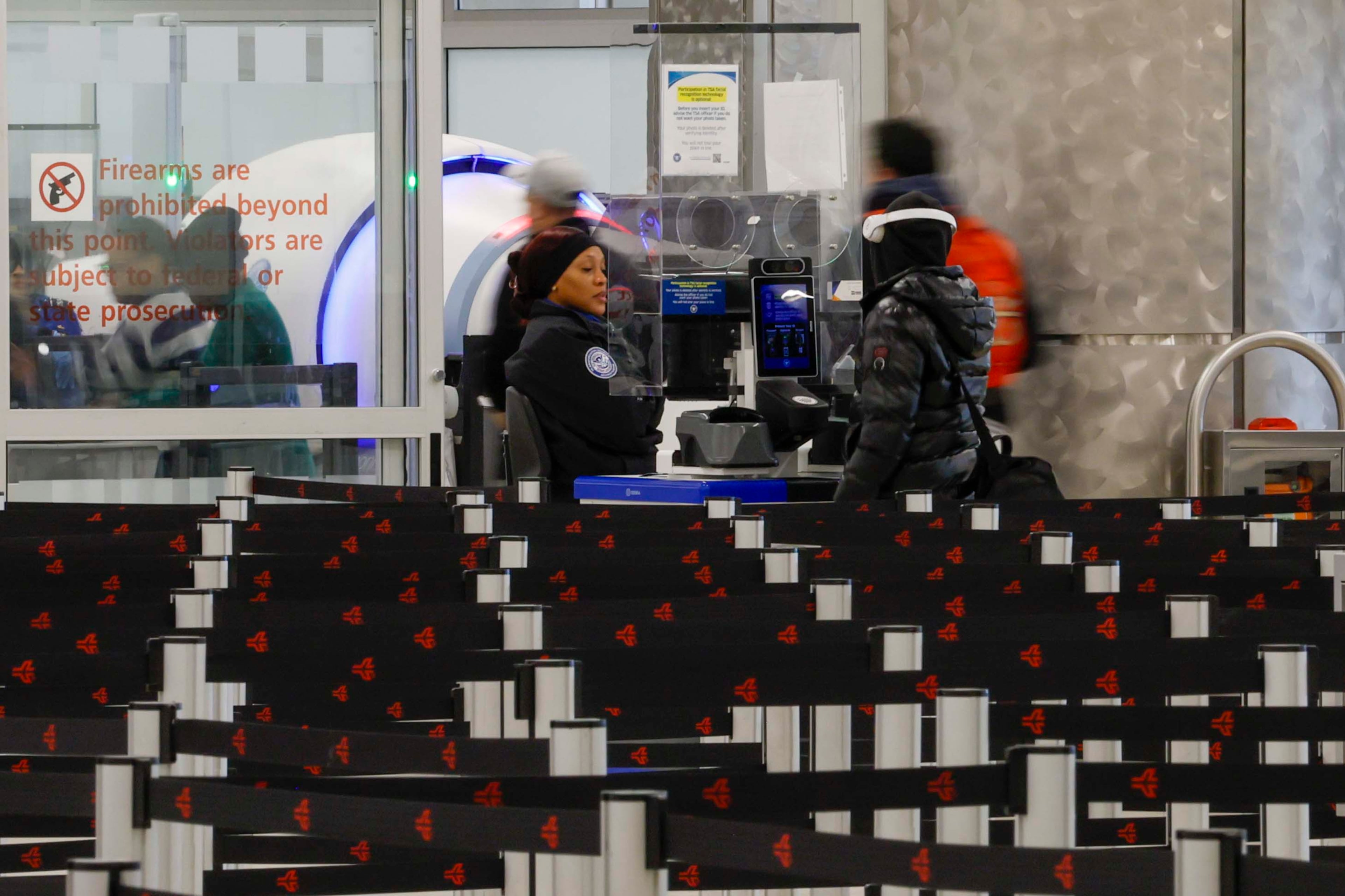 A TSA officer is seen assisting a traveler at the Main Check Point at Hartsfield-Jackson Atlanta International Airport, with no wait time on Monday, Jan. 26, 2026 amid an ice storm. According to TSA, passenger volume dropped 24% from the previous Saturday, marking the lowest level of the year. (Miguel Martinez/AJC)