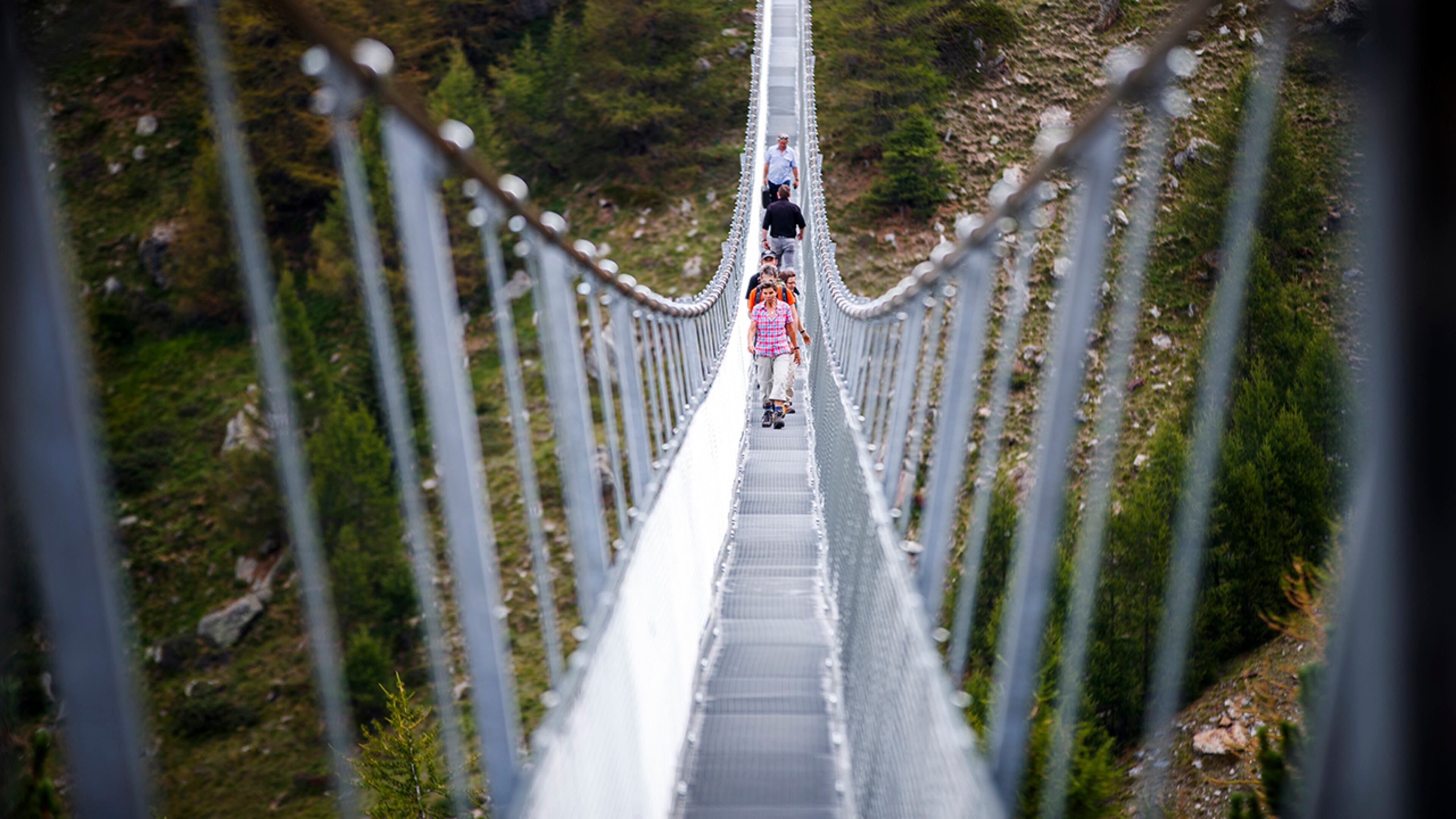 People walk on the "Europabruecke", supposed to be the world's longest pedestrian suspension bridge with a length of 494m, after the official inauguration of the construction in Randa, Switzerland, on Saturday, July 29, 2017. The bridge is situated on the Europaweg that connects the villages of Zermatt and Graechen. (Valentin Flauraud/Keystone via AP)