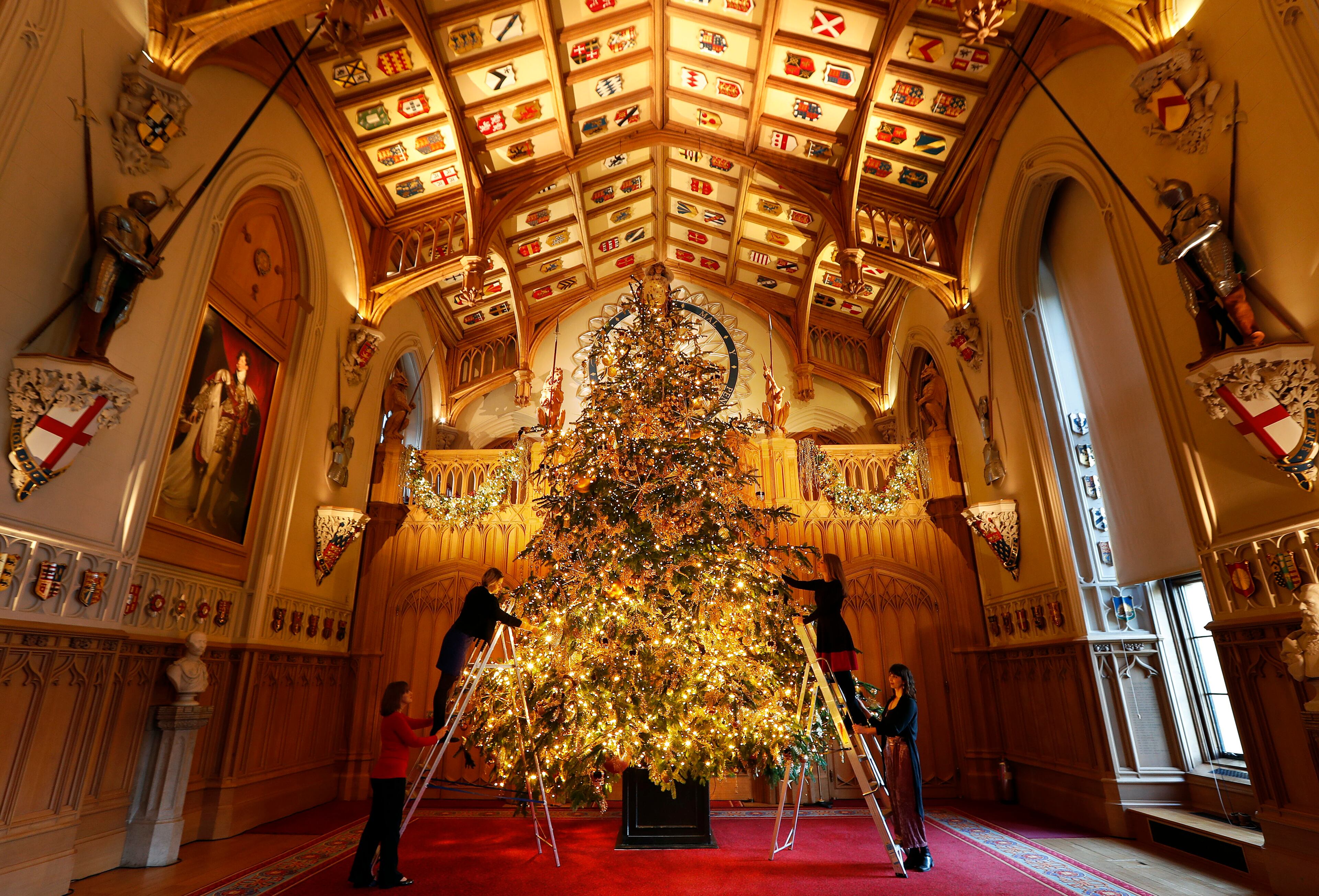A 20ft Nordmann Fir tree from Windsor Great Park, entirely dressed in gold, is decorated and stands at the end of St George's Hall, at Windsor Castle in Windsor, England, Friday, Nov. 30, 2018. (AP Photo/Frank Augstein)