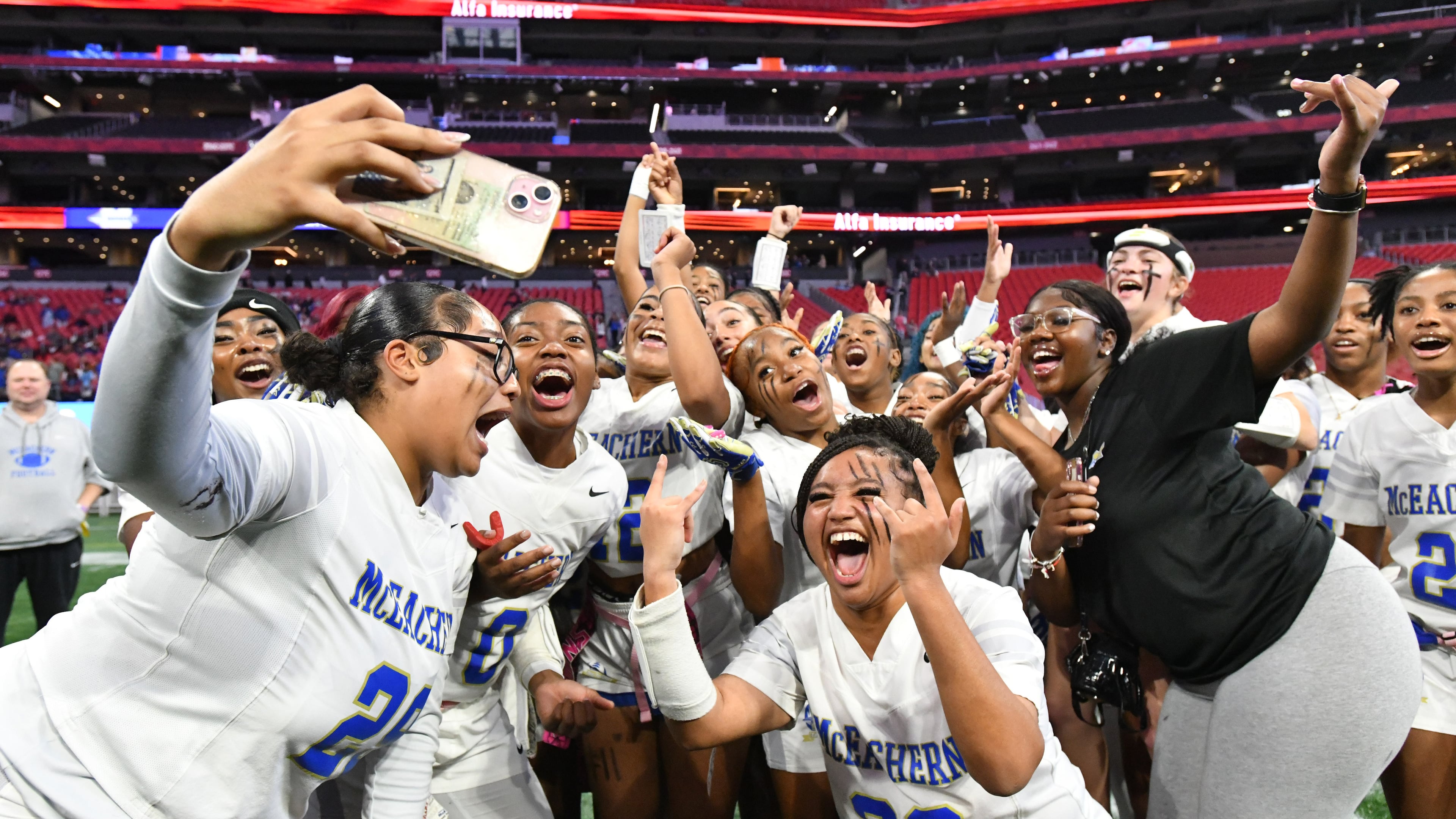 McEachern players celebrate their victory over Lambert in GHSA Division 4 Flag Football State Championship game at Mercedes-Benz Stadium, Wednesday, Dec. 18, 2024, in Atlanta. McEachern won 26-6 over Lambert. (Hyosub Shin/AJC)