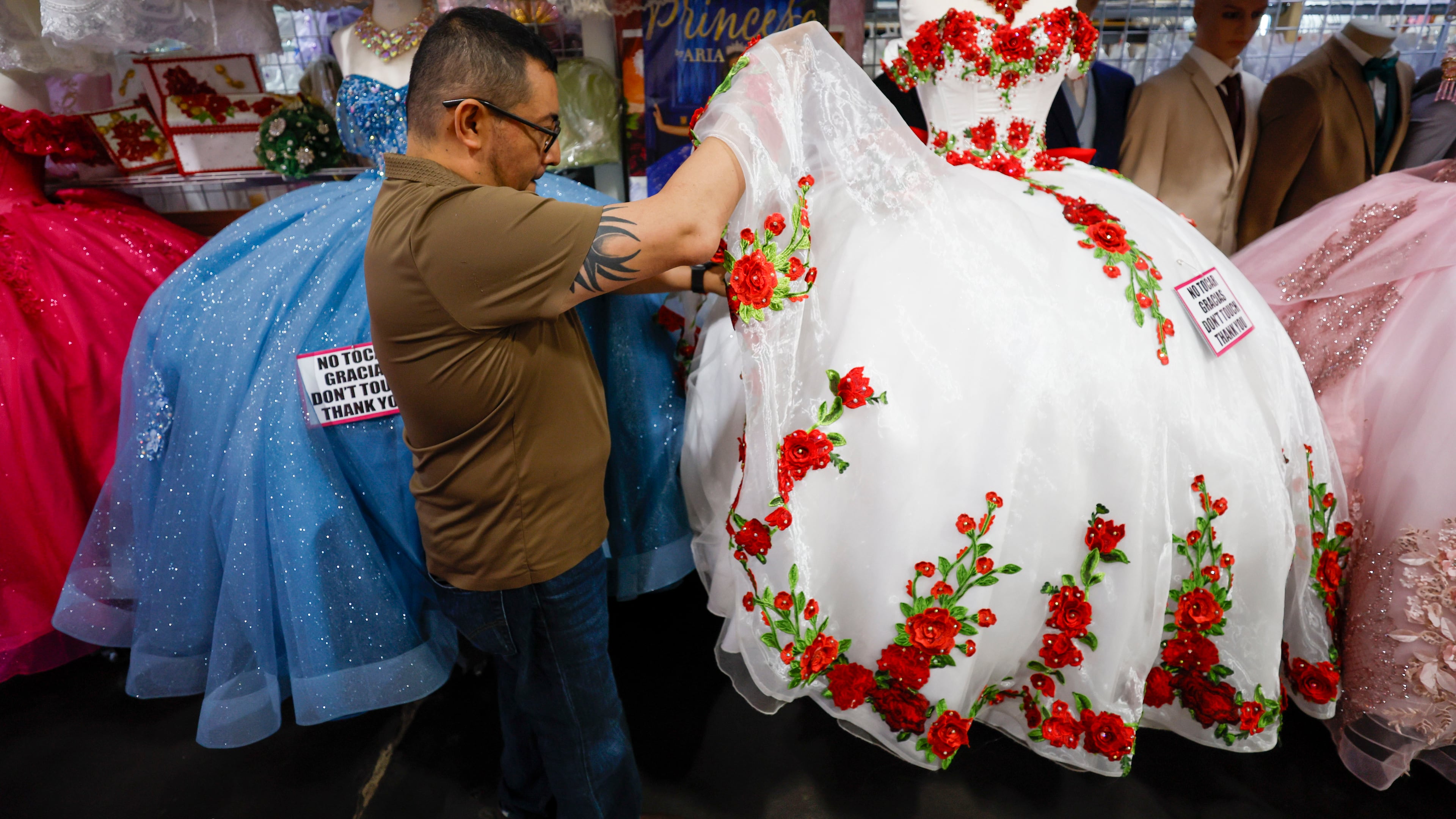 Frank Chavez, owner of Lizzy Fashion, arranging a quinceañera dress at his shop in Plaza Fiesta on Wednesday, May 7, 2025. (Miguel Martinez/AJC)