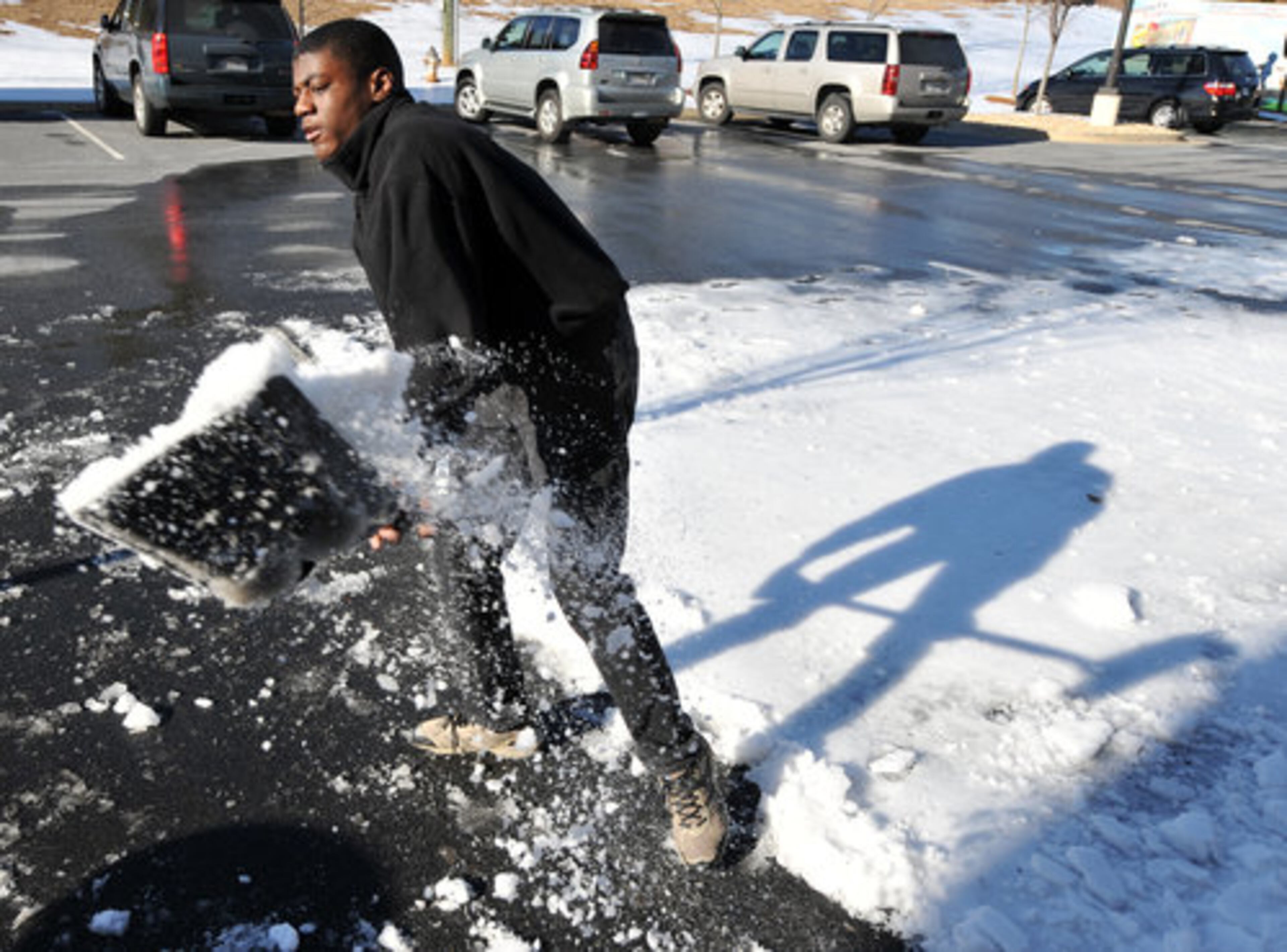Dylan Leach, 14, shovels snow to clear a parking space for his mother's business at the Suwanee Creek shopping center, which was open for business Friday.