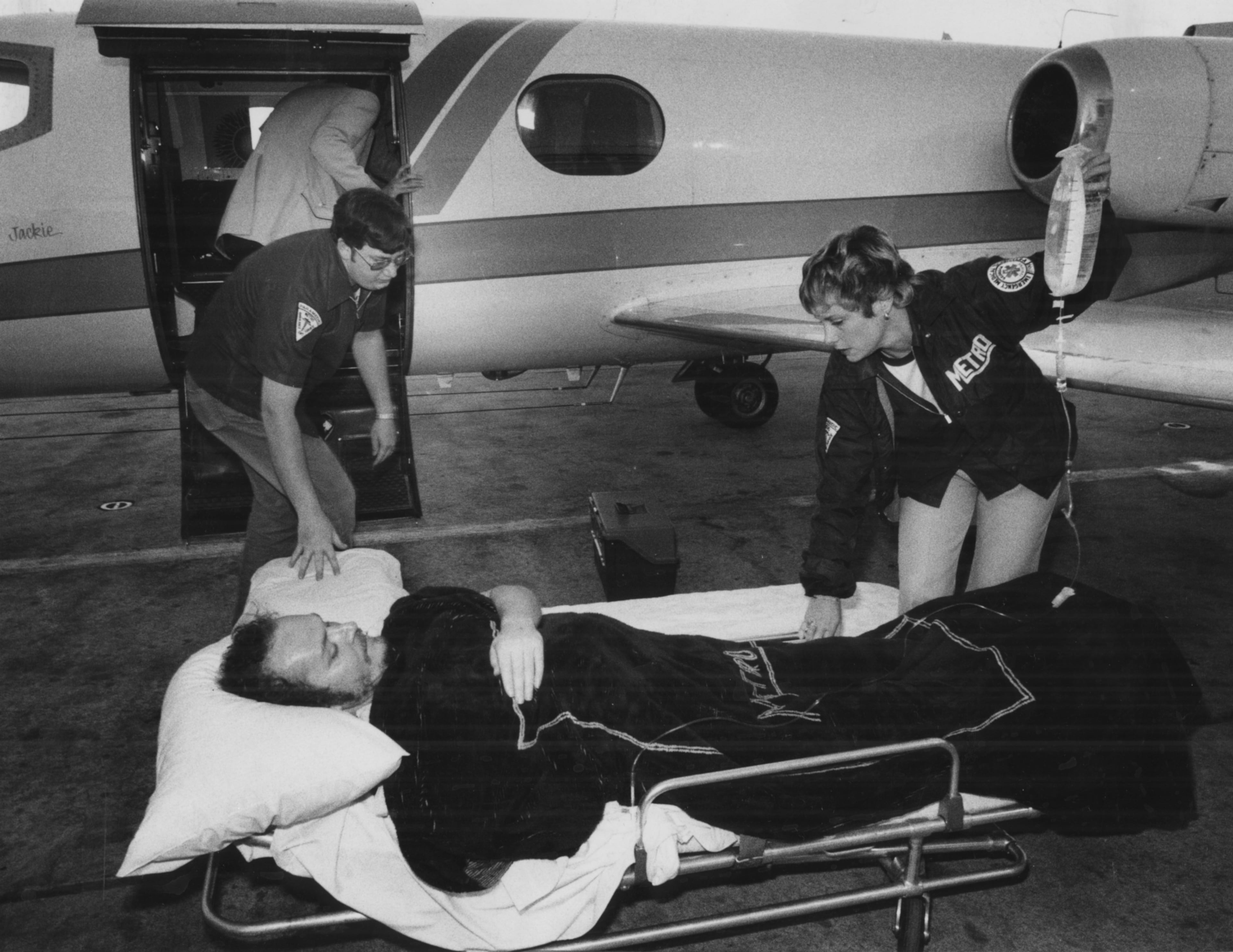 The caption for this April 14, 1978 reads: "Ambulance attendants prepare to lift Larry Flynt into plane for a flight home to Columbus, Ohio. The wounded Hustler Magazine owner appeared to be in good spirits, the attendants said. Flynt was shot in the back in downtown Lawrenceville, GA in early March." The Constitution reported on March 8 that "a little more than an hour after Flynt was shot, Judge Hughel Harrison declared a mistrial in the obscenity case, saying 'It is hard to believe this kind of thing could happen in a modern civilization.'"