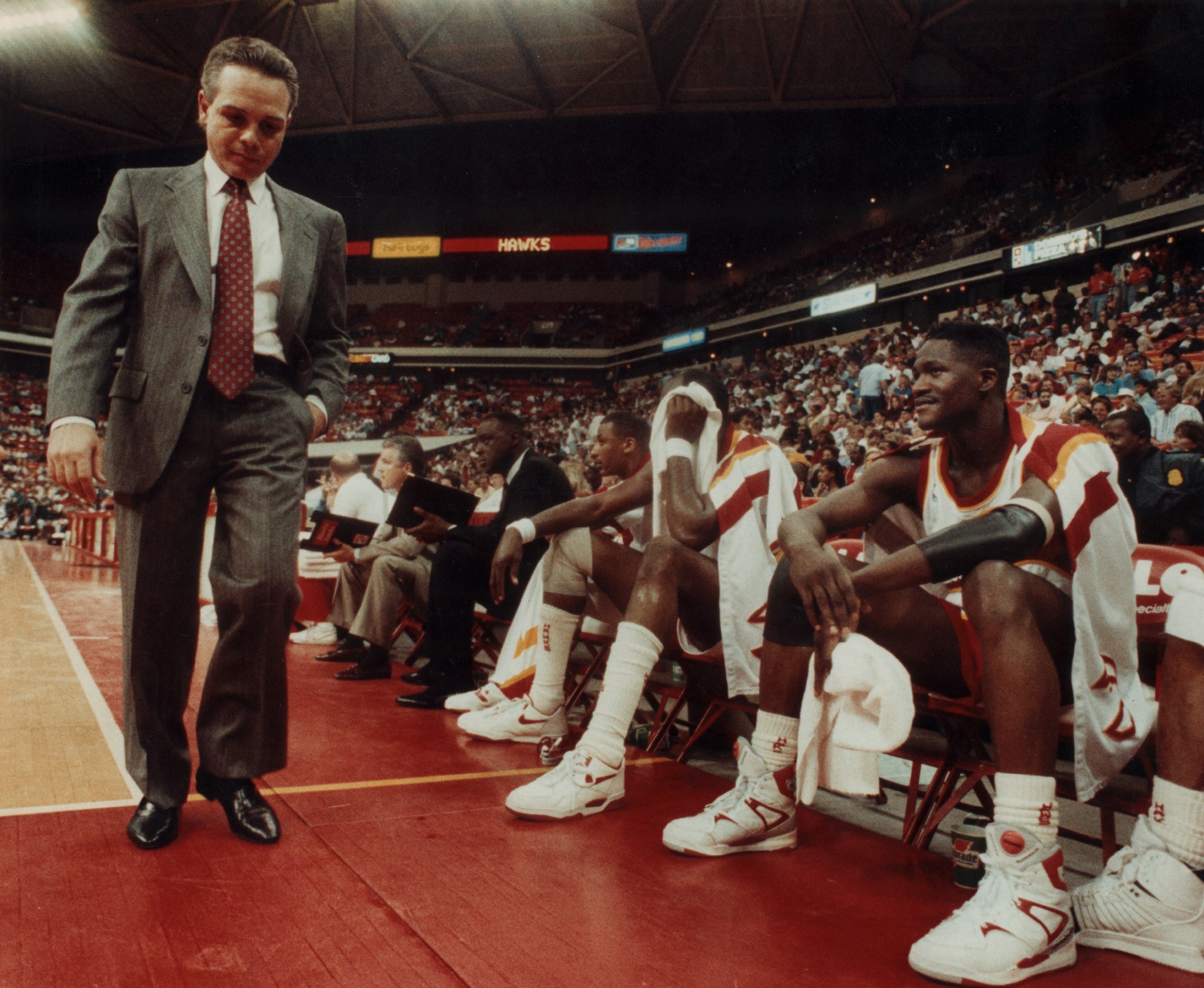 Hawks coach Mike Fratello paces the sidelines while Hawks star Dominique Wilkins waits to re-enter the game. AJC file photo