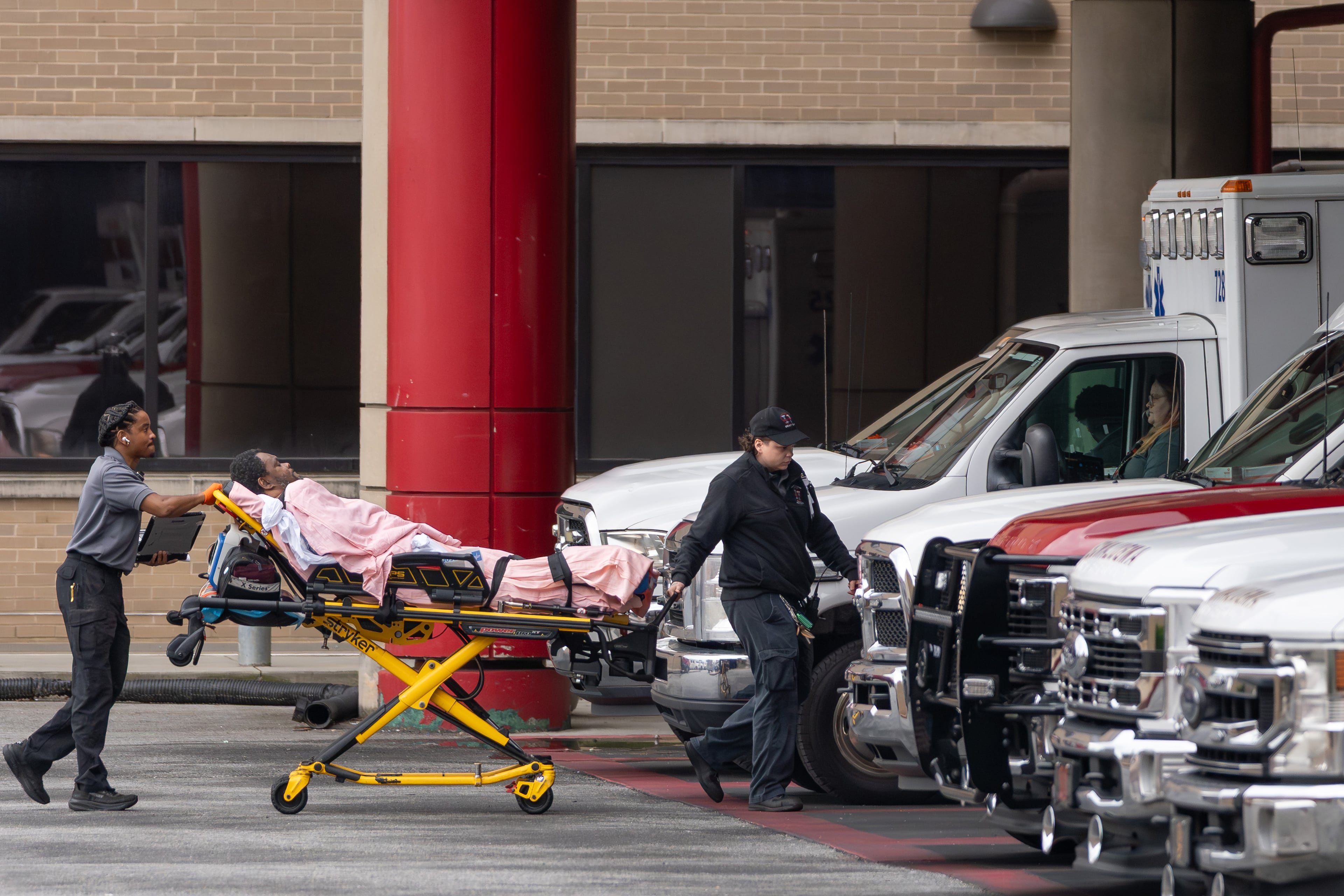 A medical crew wheels a patient across the parking area into Grady Memorial Hospital after parking across the street because the ambulance bay was full on Friday, May 1, 2026. (Ben Hendren for the AJC)