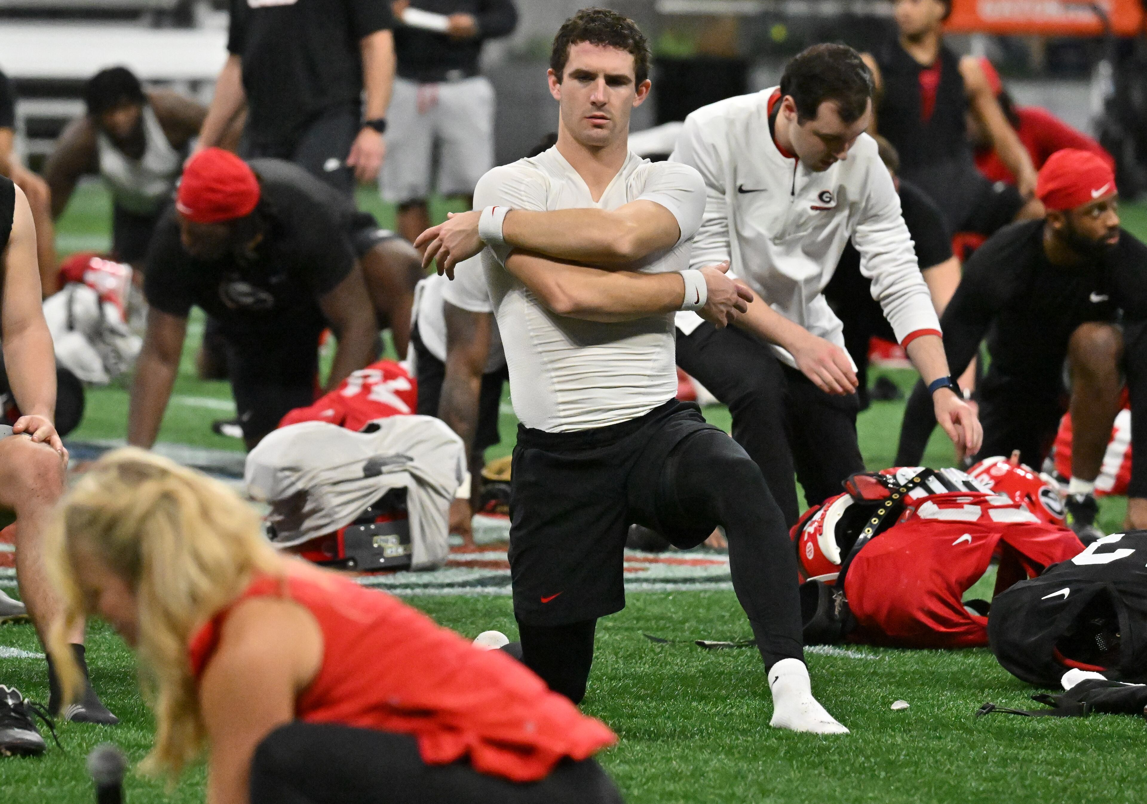 Georgia's quarterback Stetson Bennett stretches as an instructor (foreground) leads a stretch session for Georgia players during a practice session for the Chick-fil-A Peach Bowl game against Ohio State at the Mercedes-Benz Stadium on Thursday, Dec. 29, 2022, in Atlanta. (Hyosub Shin / Hyosub.Shin@ajc.com)