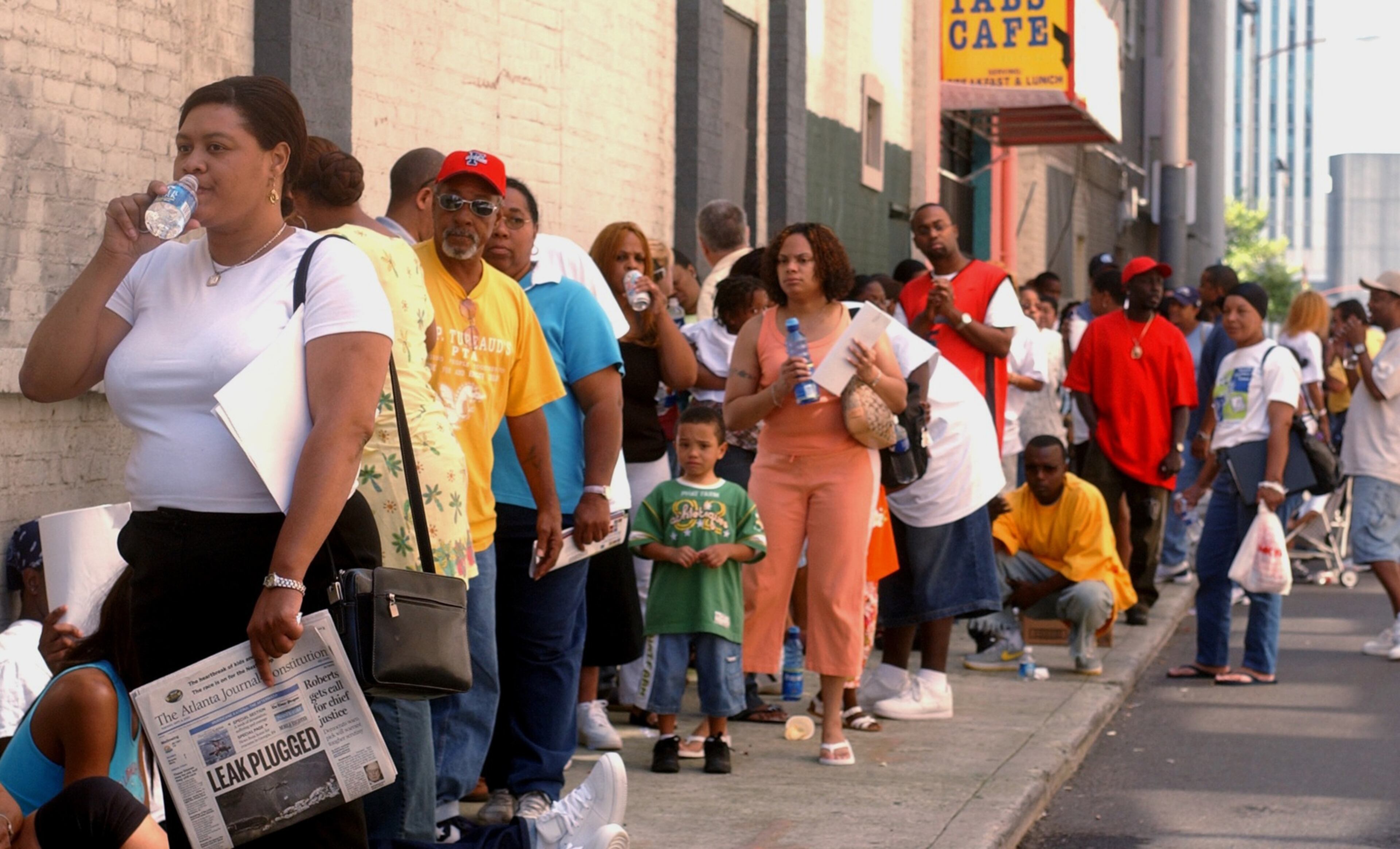 050906 - ATLANTA, GA -- Michele Allen (cq, lady in white t-shirt at left) of New Orleans sips some water as she waits in line along Tuesday, September 6, 2005 with other evacuees from Hurricane Katrina along Fairlie Street in downtown Atlanta to get help from Traveler's Aid of Metropolitan Atlanta with lodgings and other expenses. Allen has a group of ten other family members including her parents, four sisters and four children coming in from Louisiana later today and she is looking for a place for them to stay. (KIMBERLY SMITH/AJC staff)