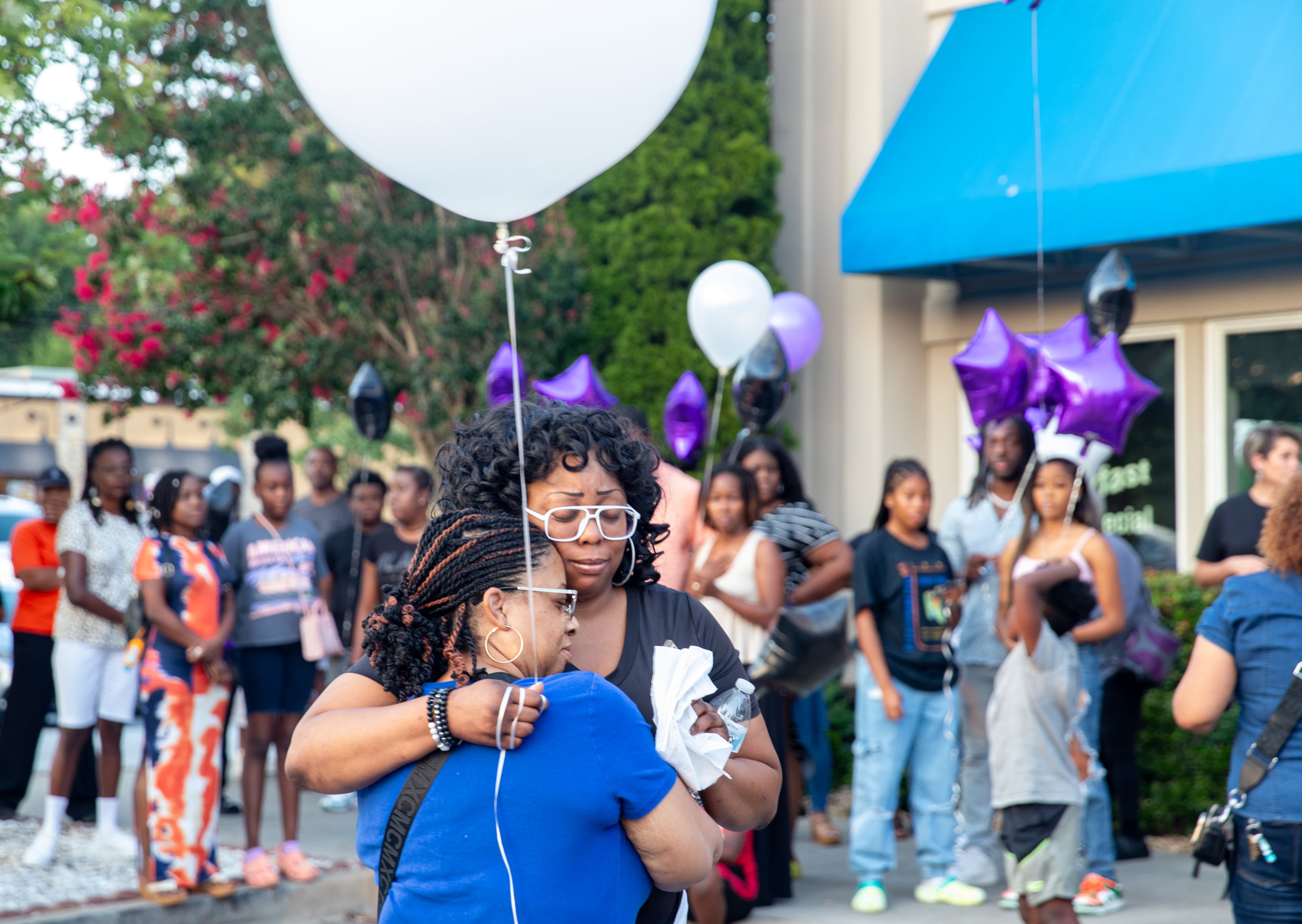 Jacob Johnson's mother Tia Morgan (right), hugs friend Laree Tolbert at a candlelight vigil and balloon release Tuesday, July 25, 2023 at the IHOP where he was allegedly killed by another teenager this month.