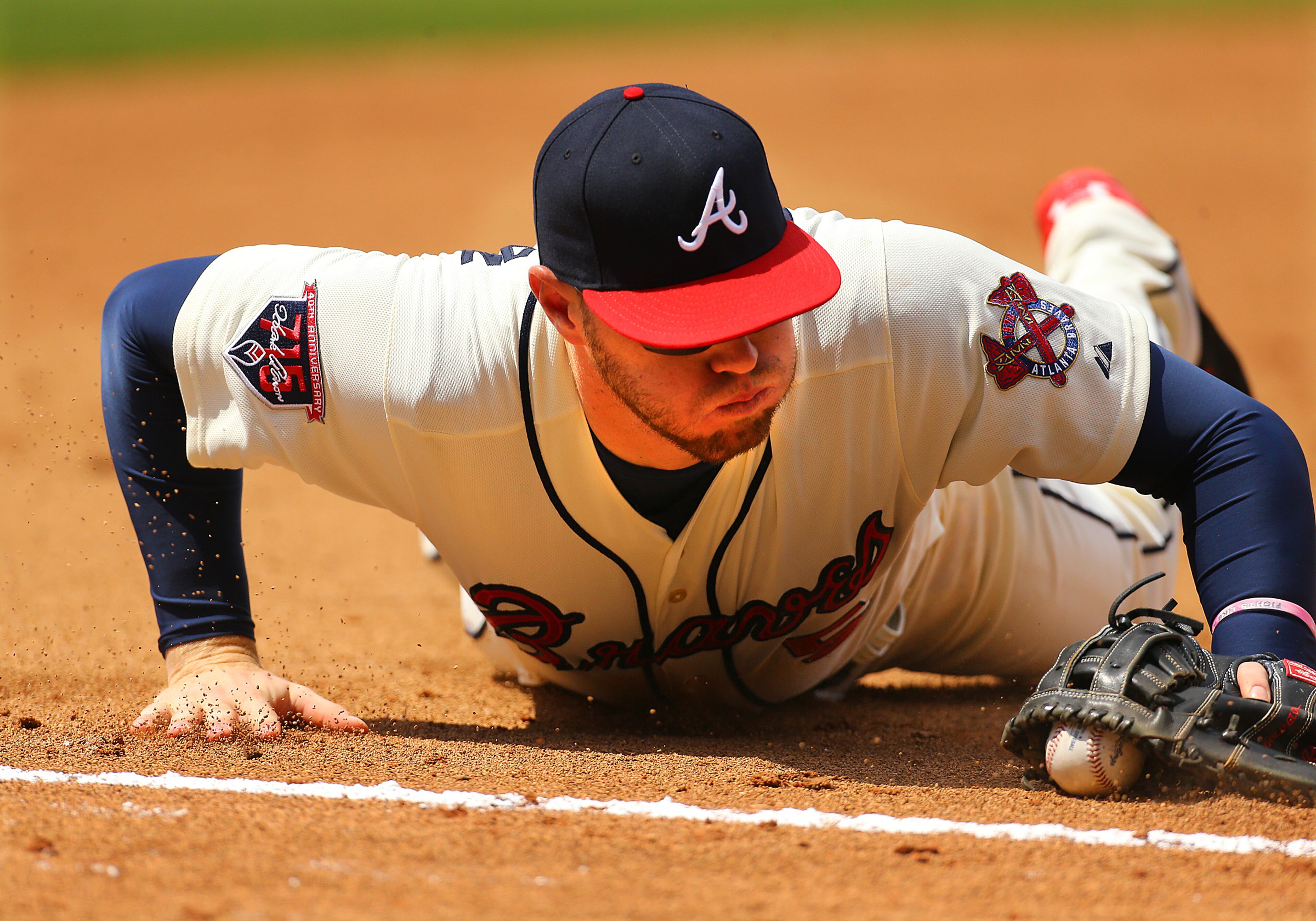 Braves first baseman Freddie Freeman makes a diving play on the ball just shy of the foul line and beats out Reds batter Billy Hamilton to first base for the out during the 6th inning. CURTIS COMPTON / CCOMPTON@AJC.COM