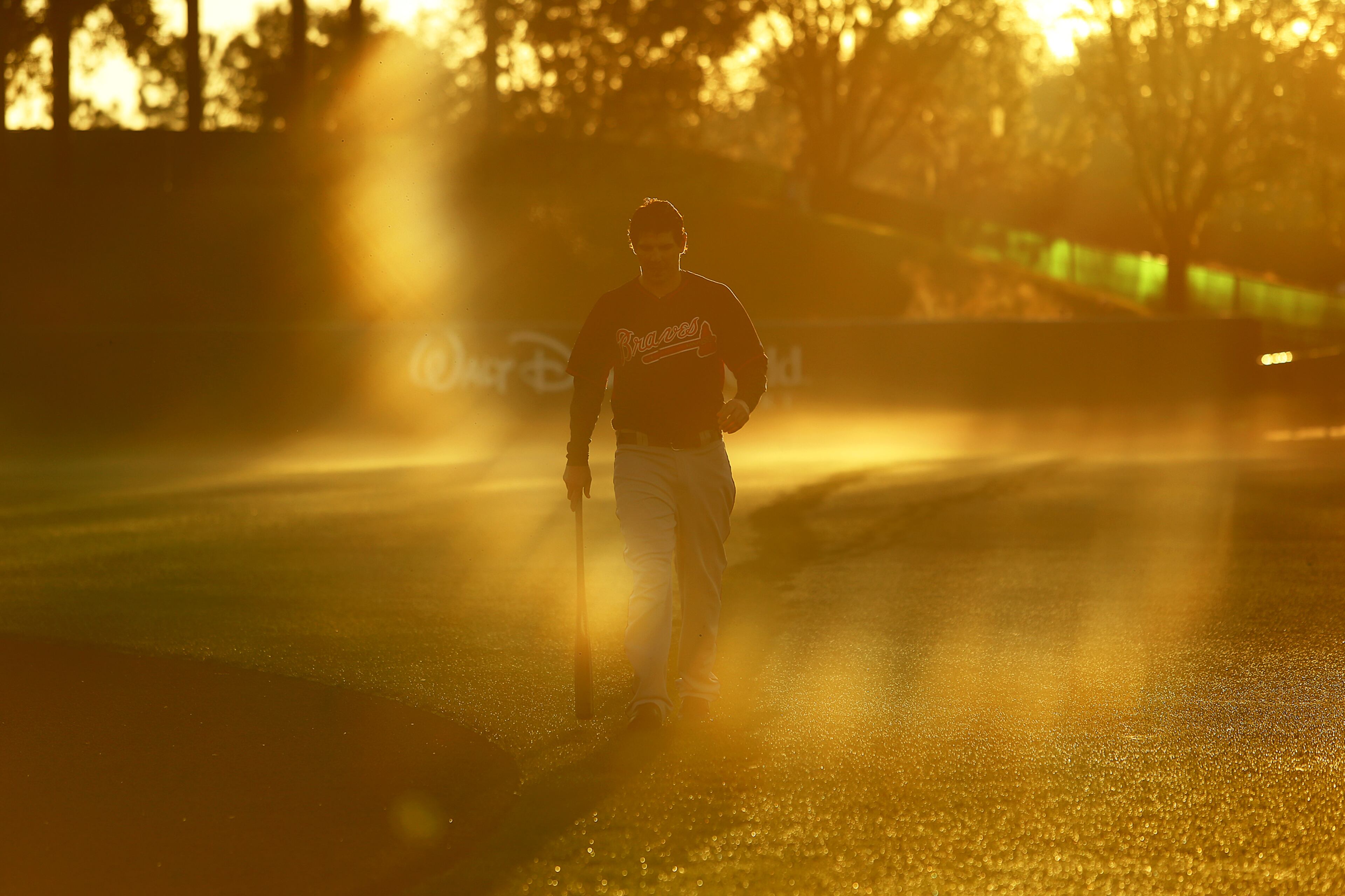 The sun flares through the mist as Braves catcher Braeden Schlehuber makes his way across the main field returning from batting practice getting an early morning sunrise start at spring training on Thursday, Feb. 20, 2014, in Lake Buena Vista, FL. CURTIS COMPTON / CCOMPTON@AJC.COM