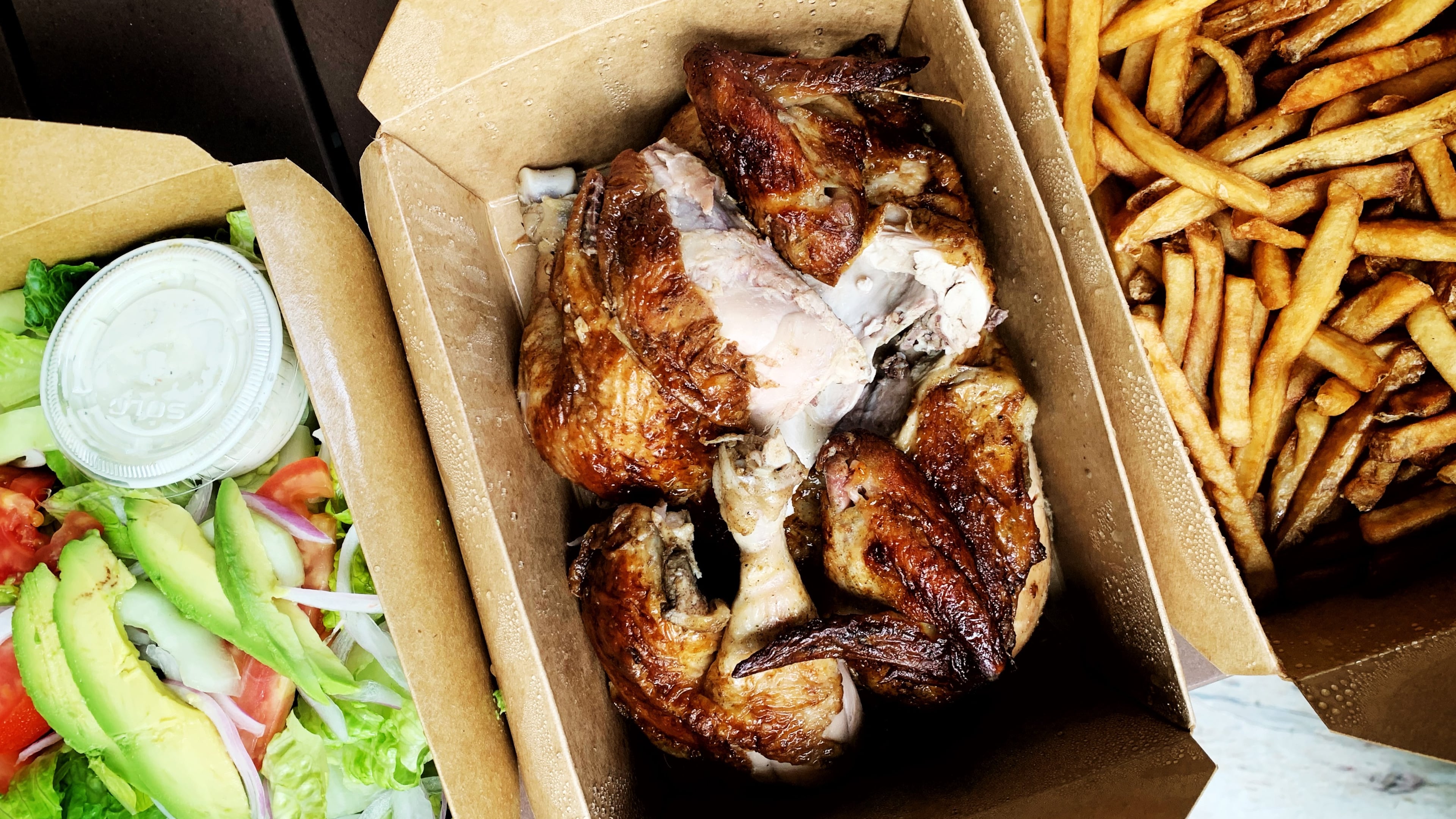 The family-style pollo a la brasa from Las Brasas in Decatur includes a Peruvian-spiced rotisserie-cooked chicken (center) with a house salad and a hearty serving of fries.