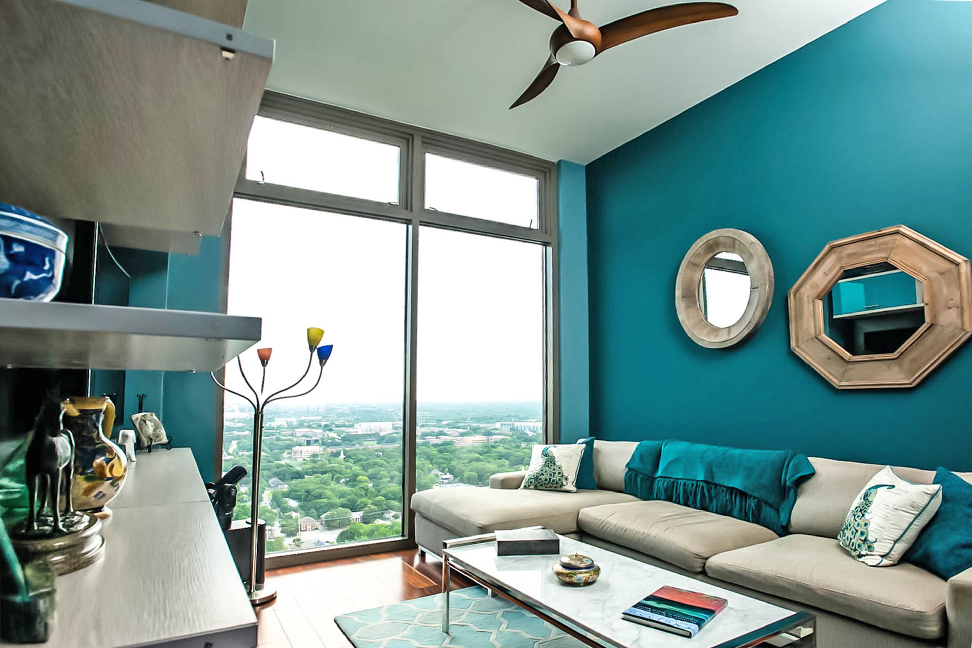 A sofa with a chaise lounge from Room & Board and coffee table with a Carrara marble top from Mitchell Gold + Bob Williams outfit the condo's entertainment room. The dark teal walls join other deep, rich tones in their Atlantic condo.