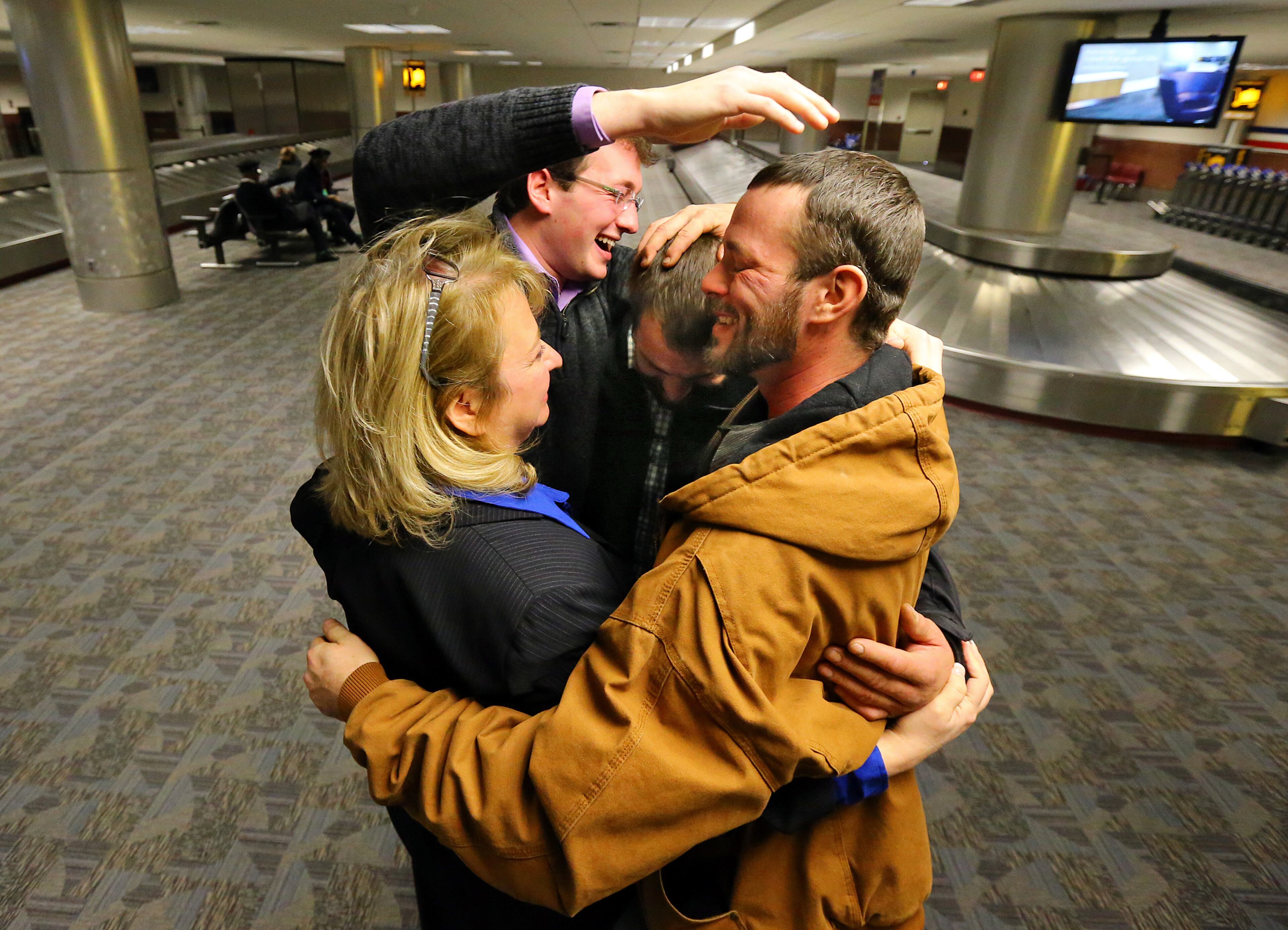 Joel Hartman, the homeless man who returned a woman's wallet he found while digging through trash hoping to find someone's leftover meal, is reunited with his family at Hartsfield-Jackson International Airport for Thanksgiving on Nov. 28, 2013, in Atlanta. His stepmother Deanna Rodecki (from left), brother Andrew Rodecki, Hartman, and his brother Erick Hordos embrace at baggage claim for the first time in a decade. Deanna Rodecki has been searching for Hartman for more than 10 years.