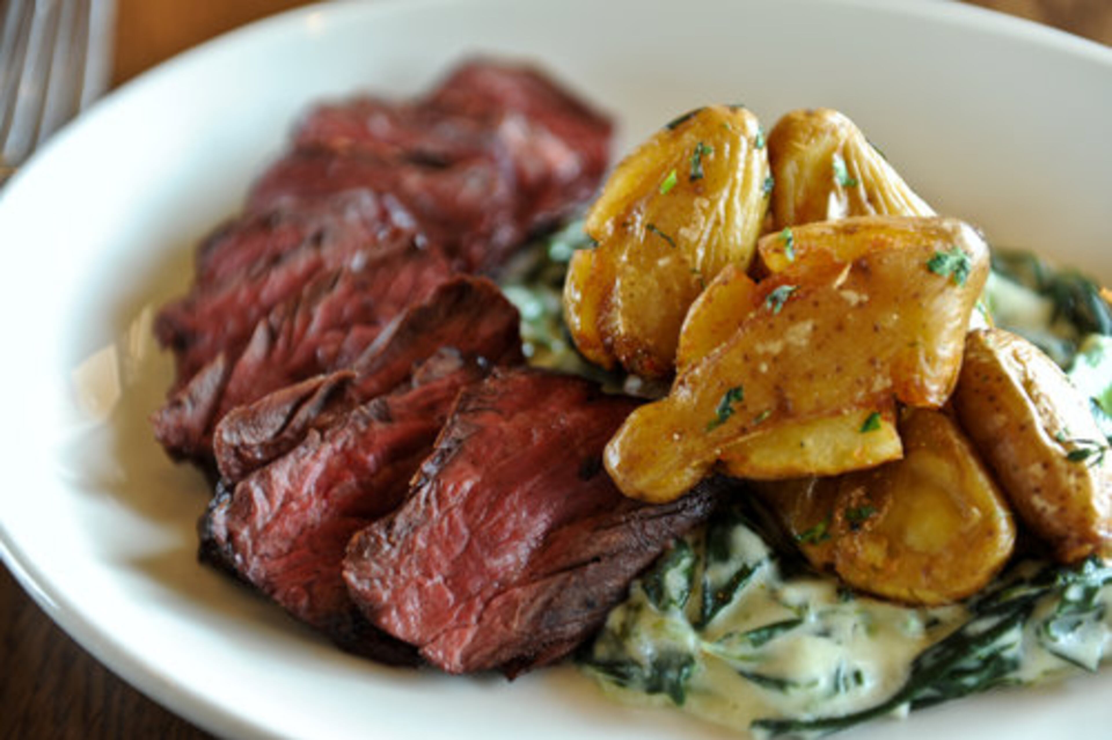 Hanger Steak with smashed and fried potatoes and creamed collards at Chicken and the Egg in Marietta. "(Chef Marc) Taft cooks with real care; when he finds a stronger vein of passion, this Chicken will be worth crossing the road and the city for." Two stars.