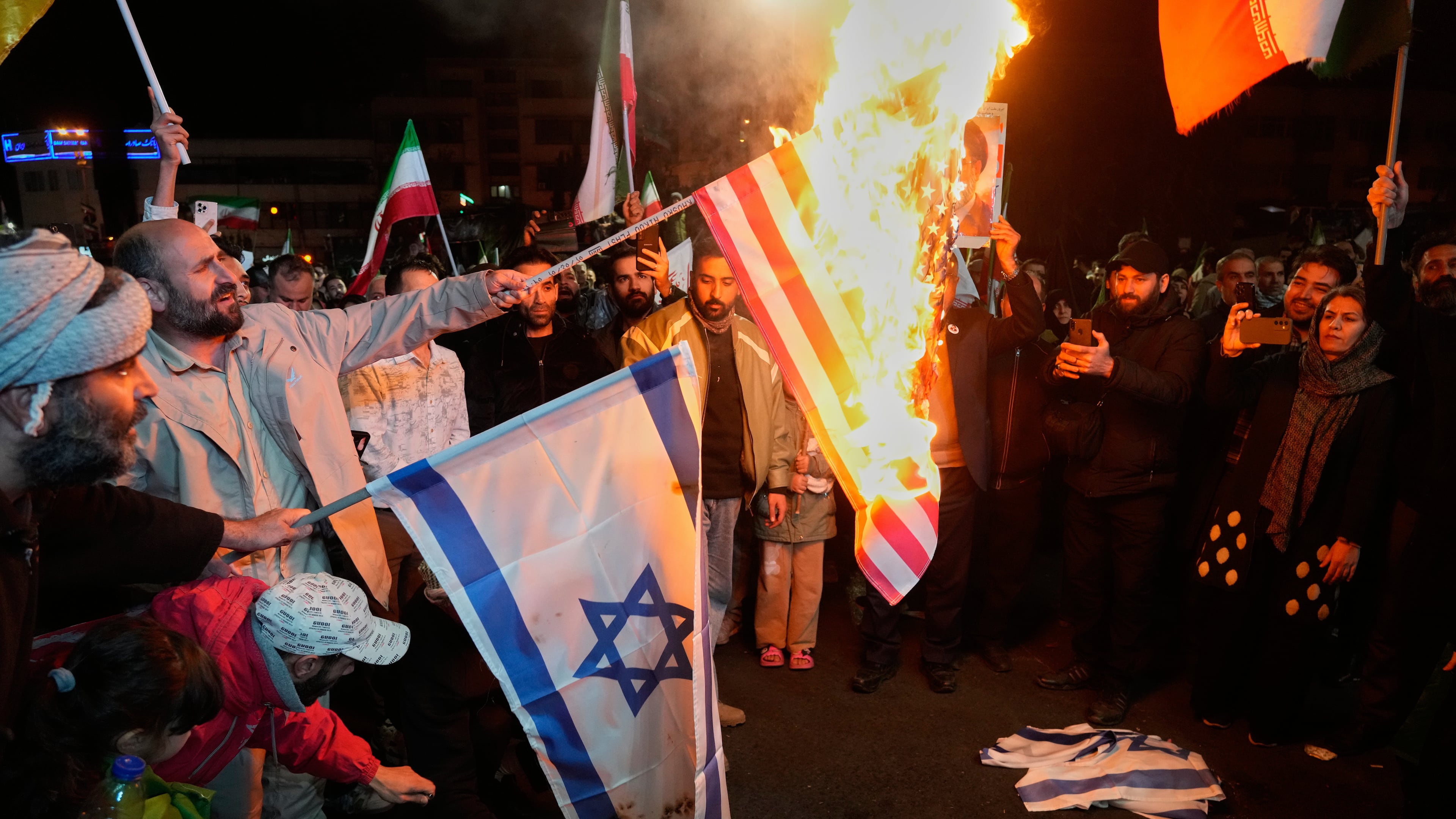 Iranian pro-government demonstrators burn the U.S. and Israeli flags during a gathering after announcement of a two-week ceasefire in the war with the United States and Israel, at the Enqelab-e-Eslami, or Islamic Revolution, Square, in Tehran, Iran, Wednesday, April 8, 2026. (AP Photo/Vahid Salemi)