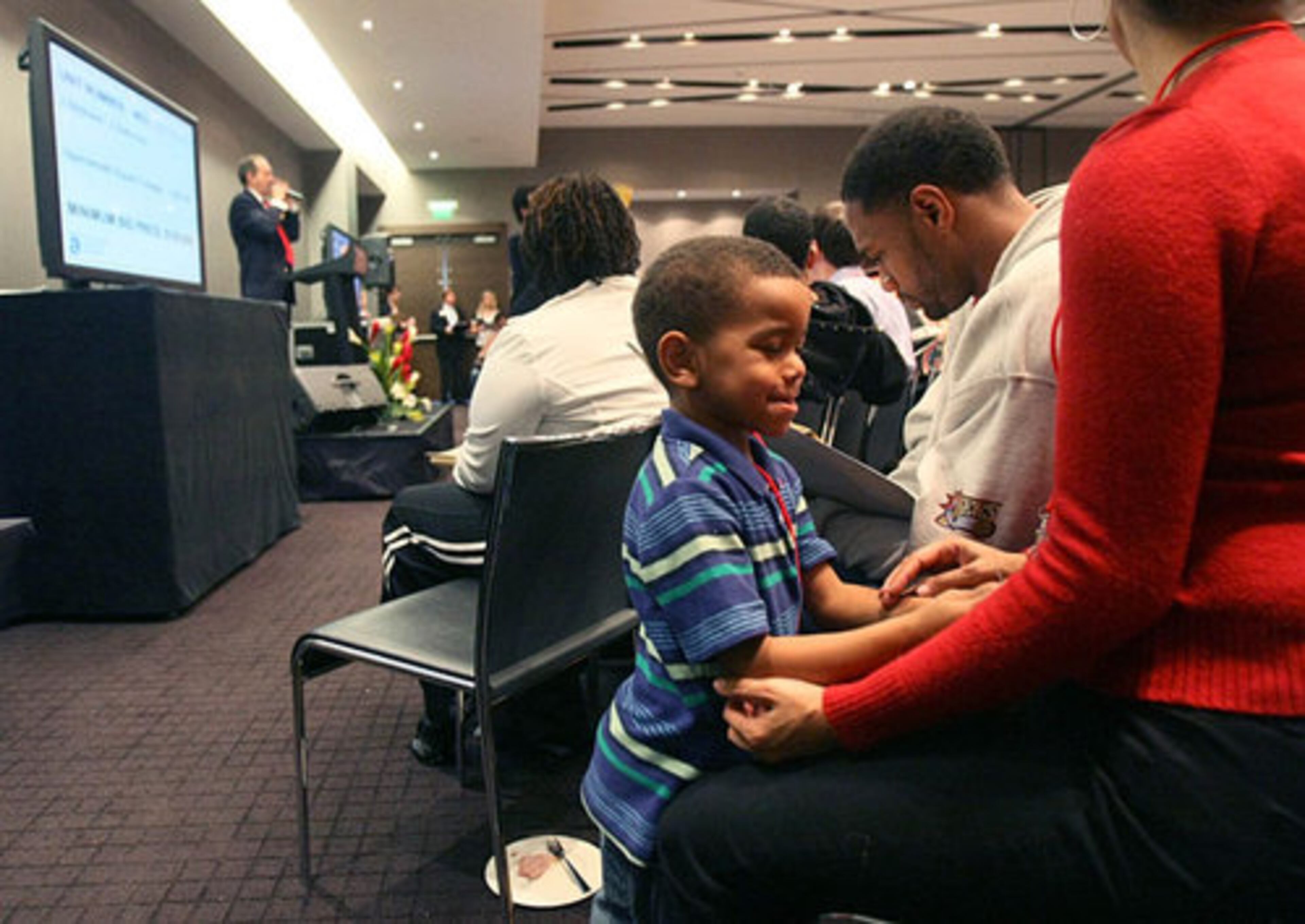 Sage Ayres, 3, of Grayson, plays with his mother Natasha Ayres as his father Robert Ayres, center, pays attention to the auction. The Ayres later bought a 1 bedroom 1 bath condo.