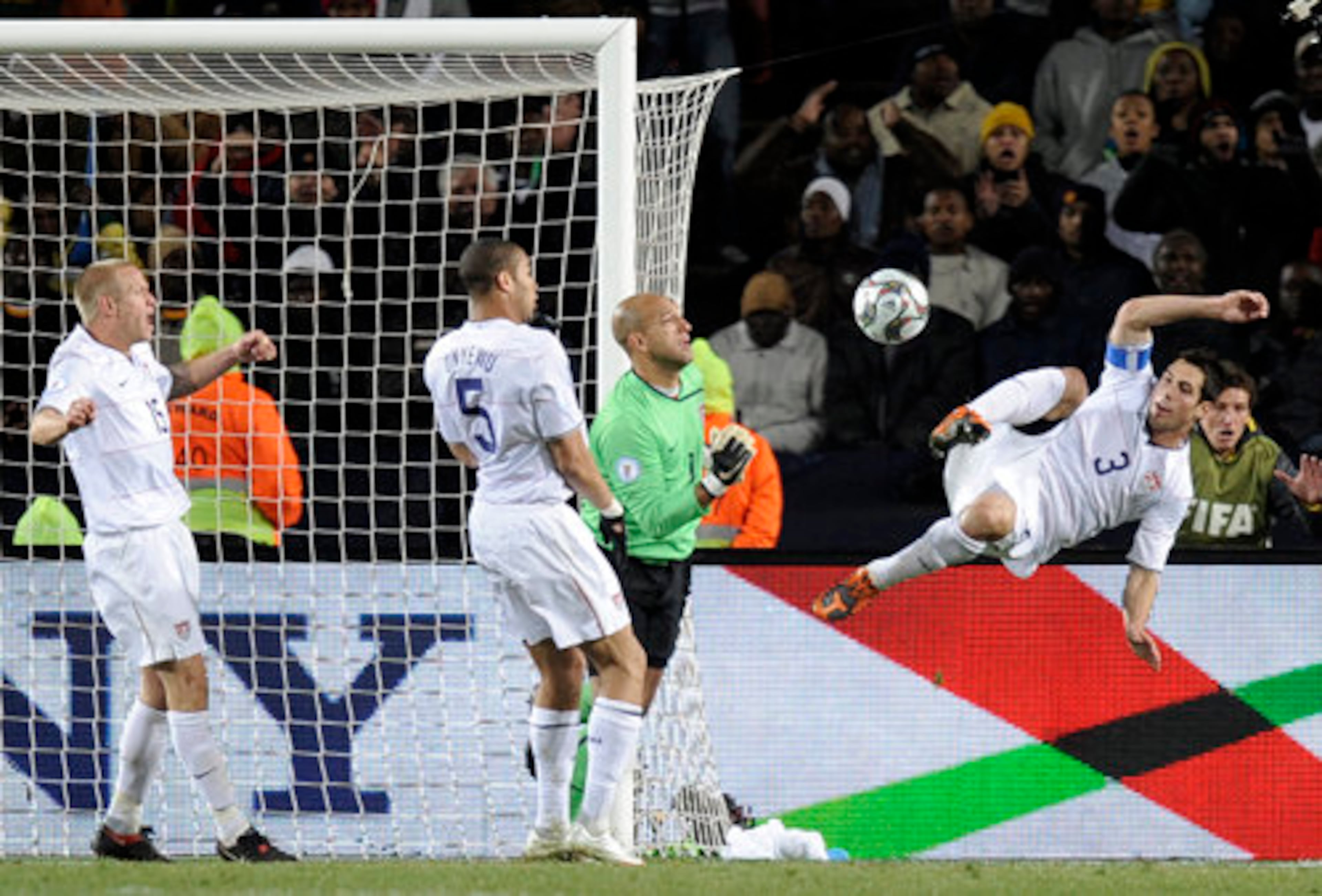 USA's Carlos Bocanegra (right) assist goalkeeper Tim Howard in a save.