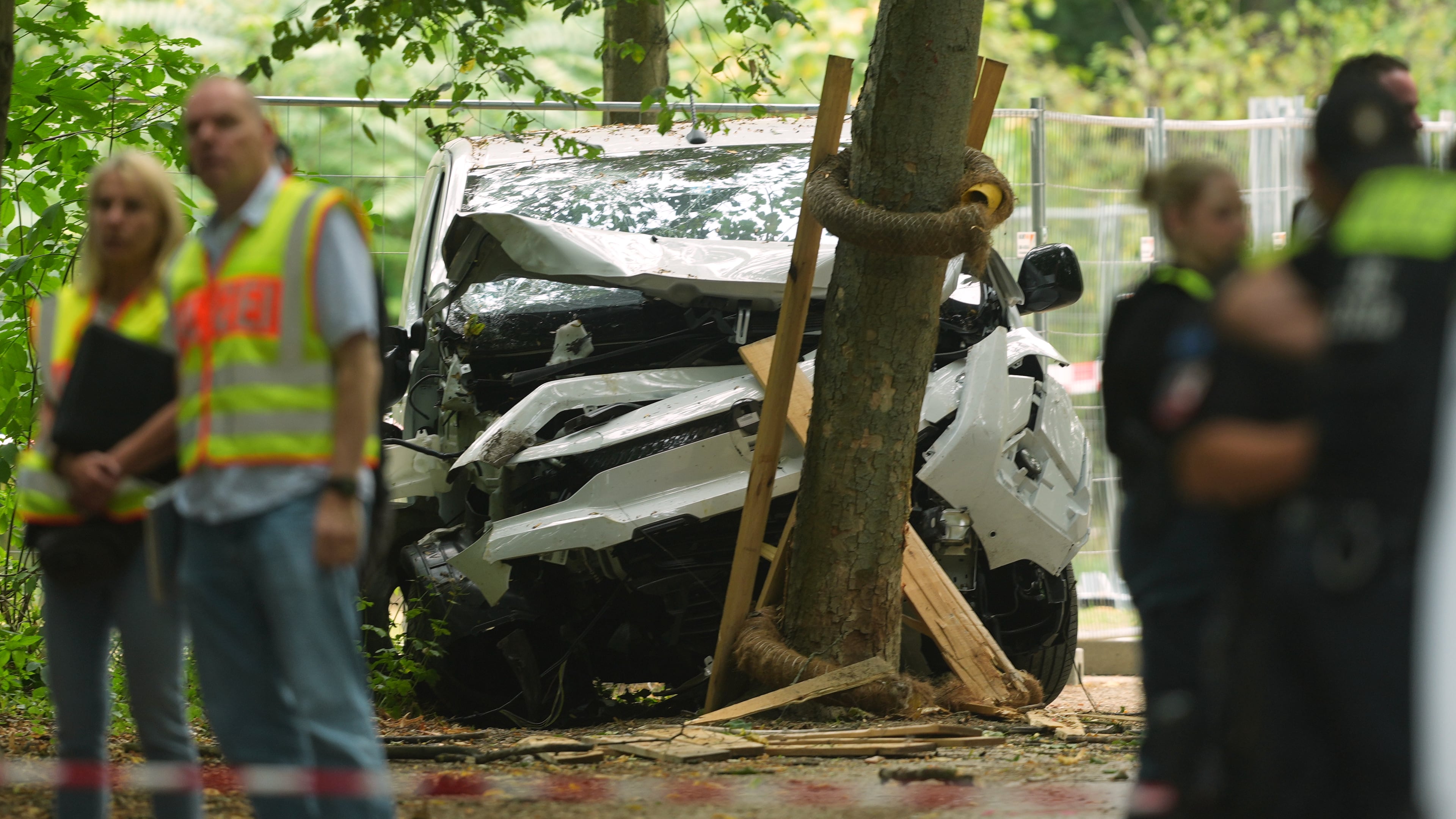 Police officers stand near a vehicle crashed into a tree after driving into a crowd near Berlin's annual Pride event, in Berlin, Germany, Sunday, July 26, 2026. (AP Photo/Markus Schreiber)