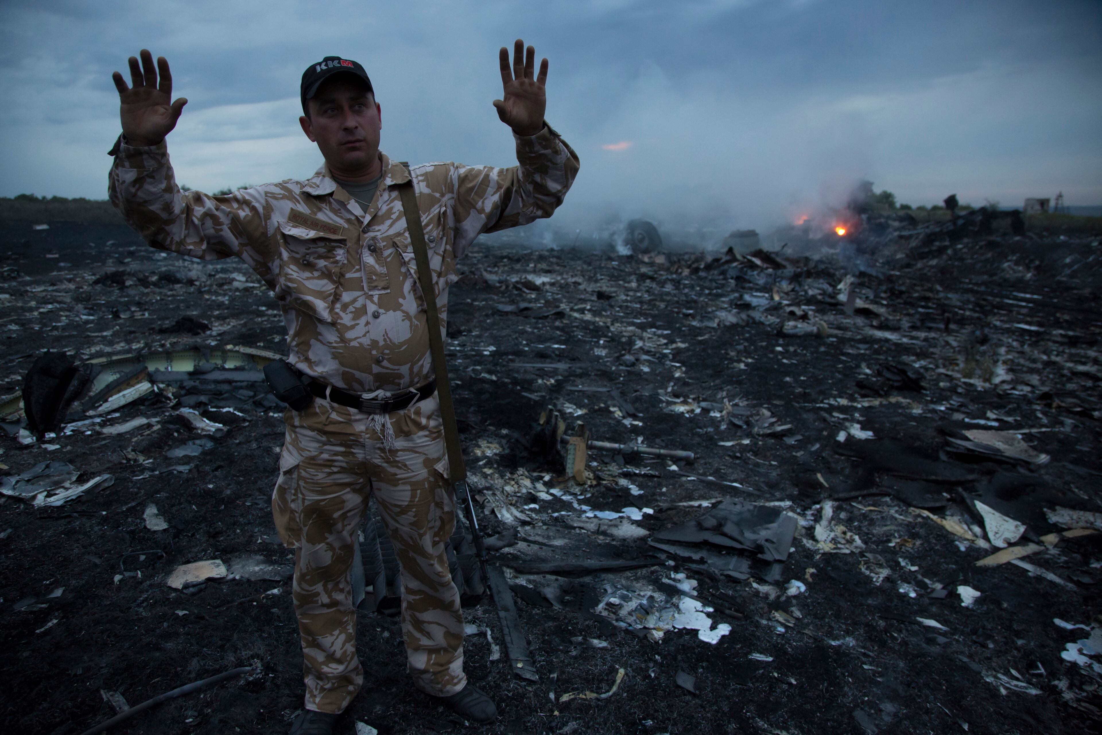 A man gestures at a crash site of a passenger plane near the village of Grabovo, Ukraine, Thursday, July 17, 2014. Ukraine said a passenger plane carrying 295 people was shot down Thursday as it flew over the country, and both the government and the pro-Russia separatists fighting in the region denied any responsibility for downing the plane. (AP Photo/Dmitry Lovetsky)