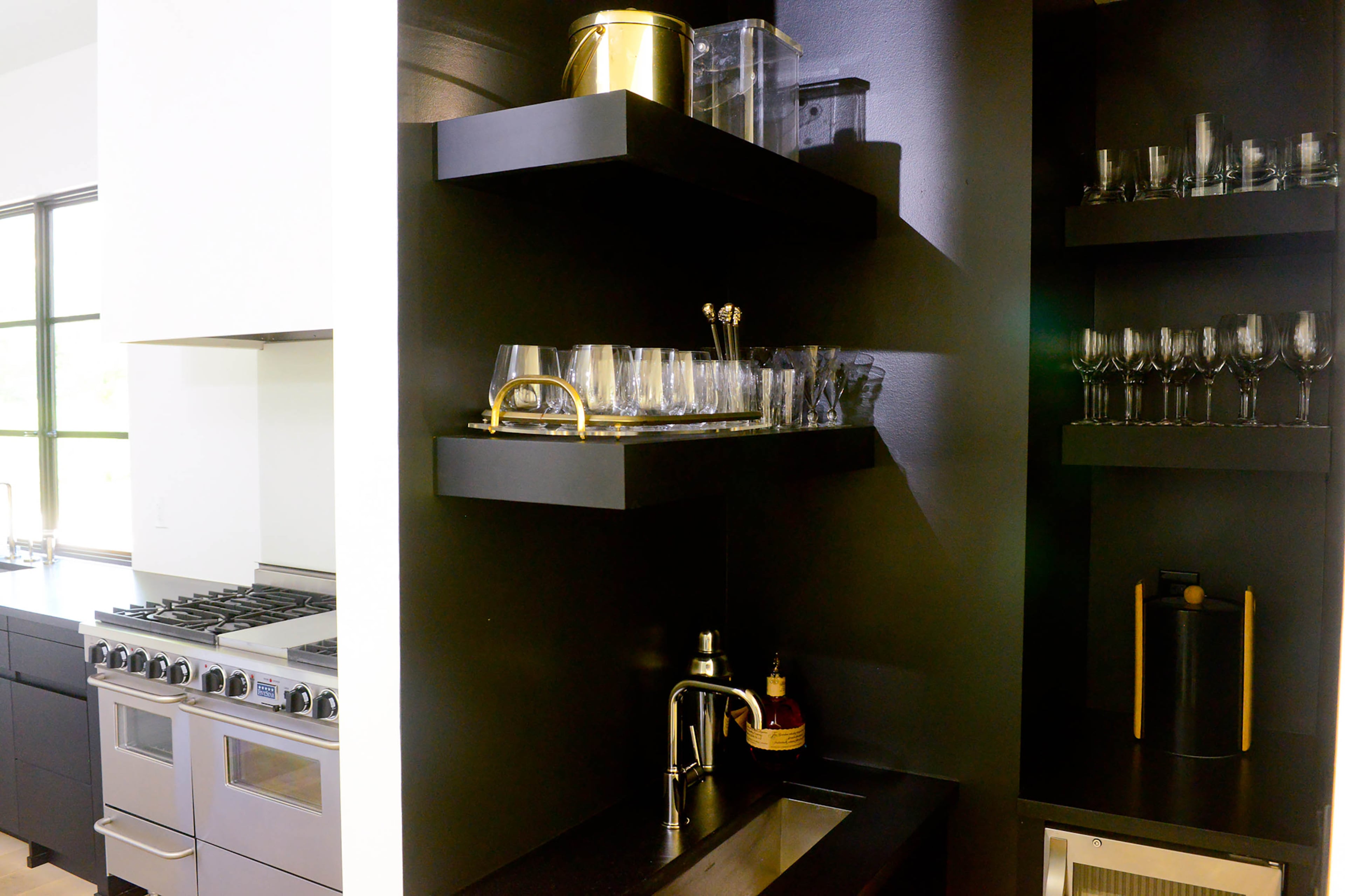 Contrasting with the bright white kitchen, the adjacent bar area is painted Benjamin Moore Black.