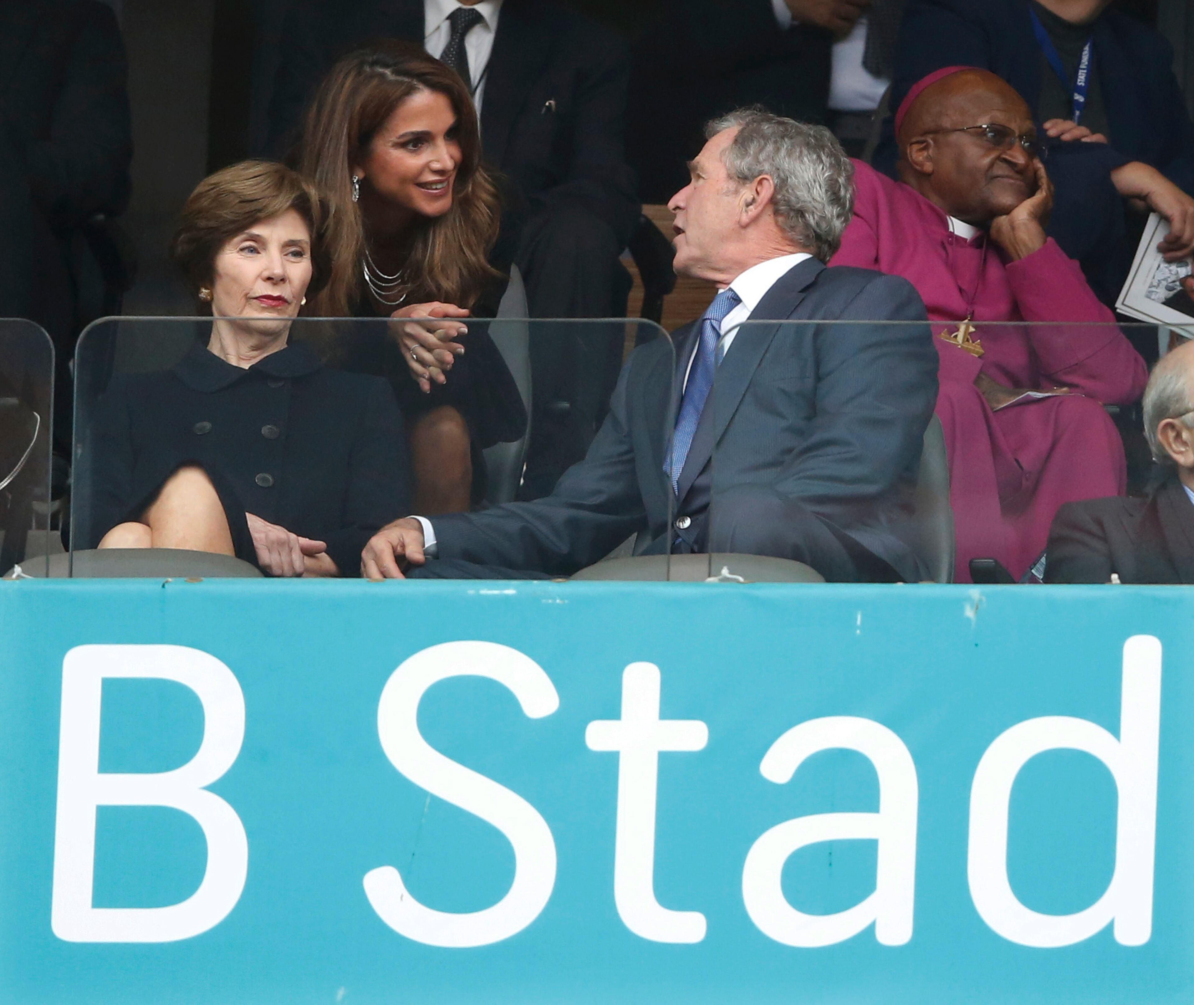 Jordan's Queen Rania, center, speaks with Former U.S. President George W. Bush and his wife Laura during the memorial service for former South African president Nelson Mandela at the FNB Stadium in Soweto near Johannesburg, Tuesday, Dec. 10, 2013. Right is Retired Anglican Archbishop Desmond Tutu. (AP Photo/Matt Dunham)
