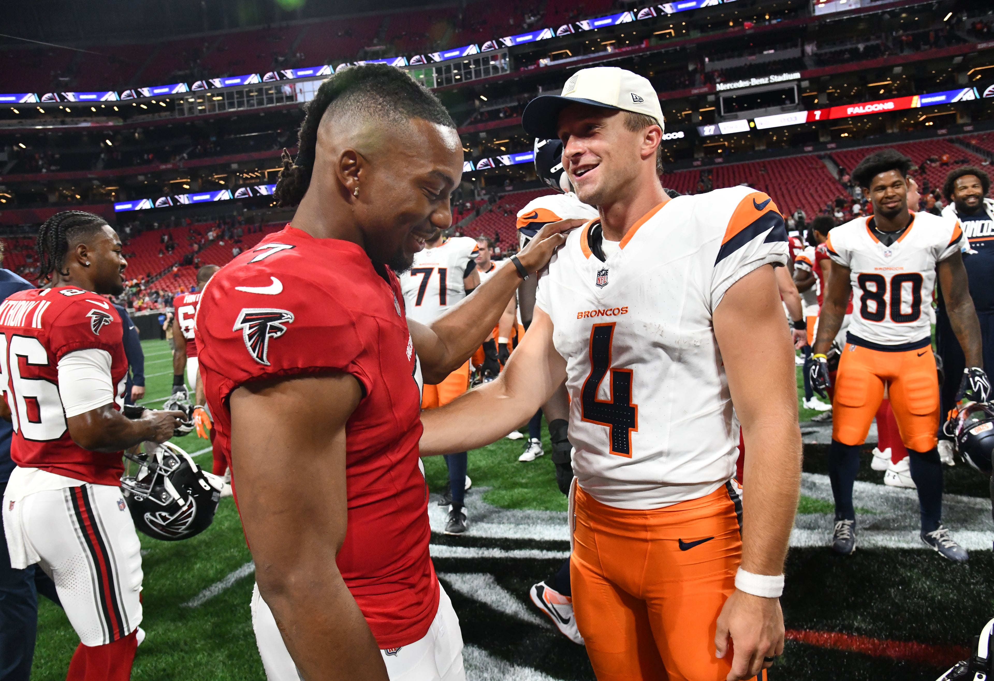 Falcons running back Bijan Robinson (left) and Broncos quarterback Sam Ehlinger greet each other after their preseason game at Mercedes-Benz Stadium on Friday, Aug. 14, 2026, in Atlanta. The Denver Broncos won, 27-7, over the Atlanta Falcons. (Hyosub Shin/AJC)